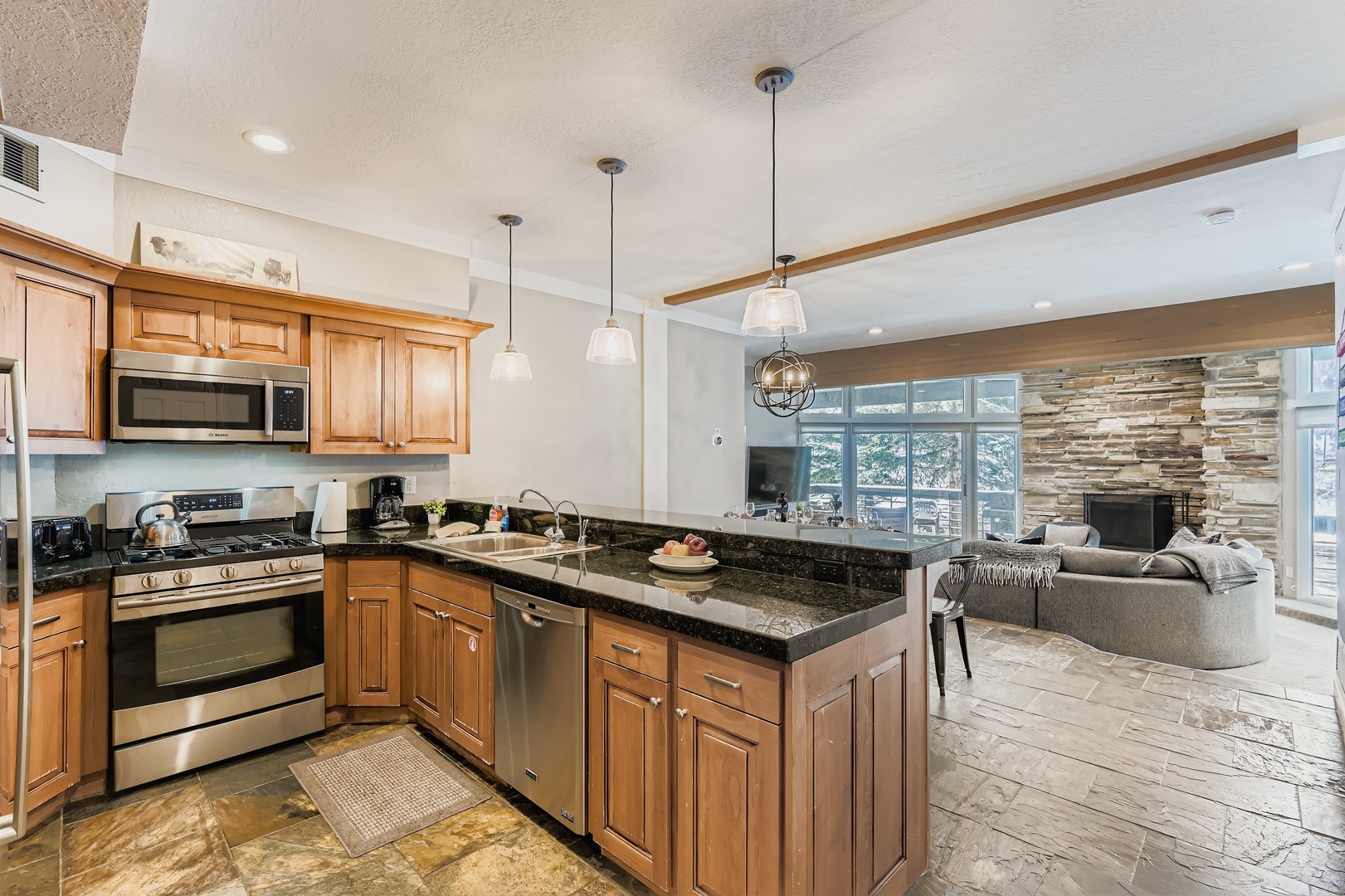 A bright, open kitchen awaits with granite counters, stainless appliances, and everything you need to whip up meals. Beyond, your living space flows seamlessly with cozy seating and mountain views through expansive windows.