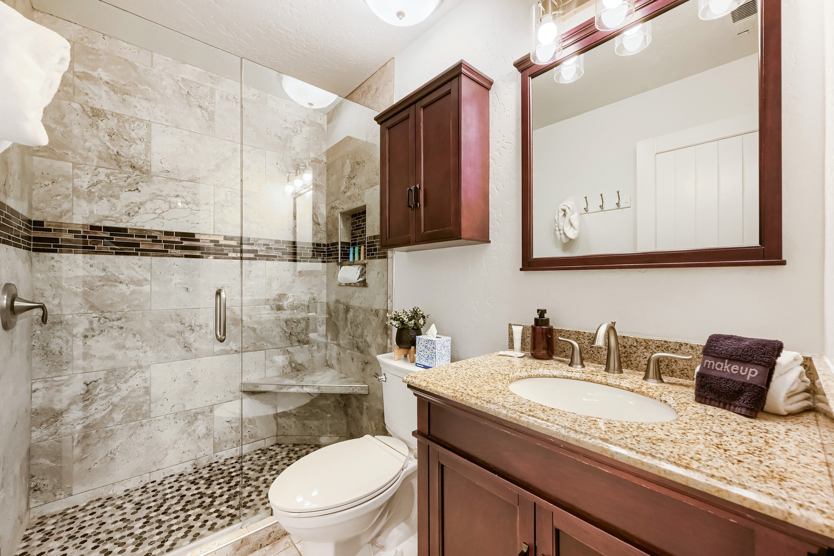 Your elegant bathroom features a spacious walk-in shower with beautiful tile work, granite countertops, and thoughtful storage with custom cabinetry—perfect for refreshing each morning.