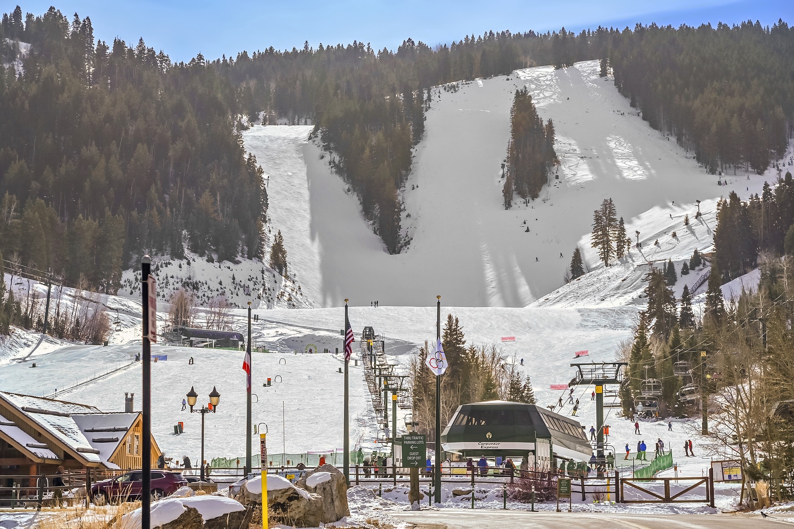 Snow-covered ski slopes stretch across forested mountains with ski lifts and winter sports facilities visible throughout the resort area.