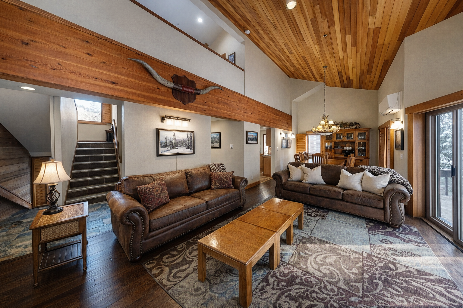 Relax in this spacious living room with rich leather sofas and warm wood beams, perfect for gathering after your mountain adventures.