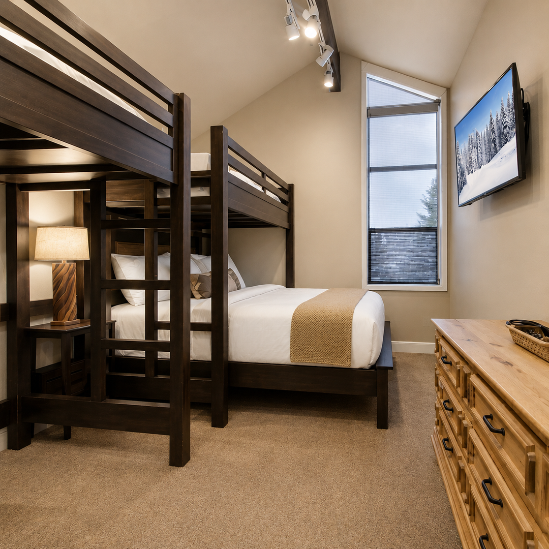 Your cozy mountain retreat features inviting bunk beds with crisp white linens, warm wood tones, and a flat-screen TV for movie nights after a day of adventure.