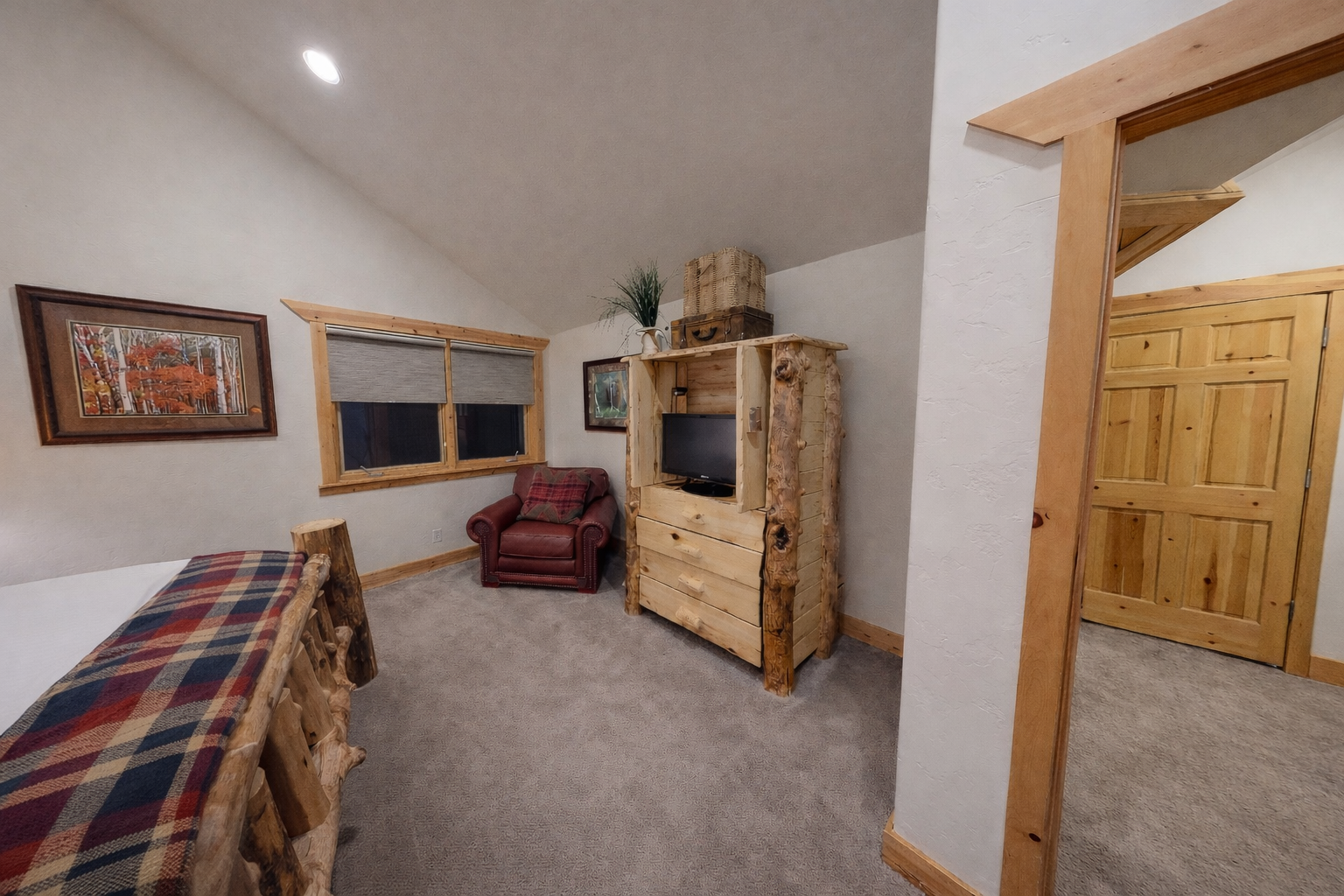 Unwind in your cozy retreat with rustic log furniture, plaid bedding, and a comfy chair for evening relaxation.