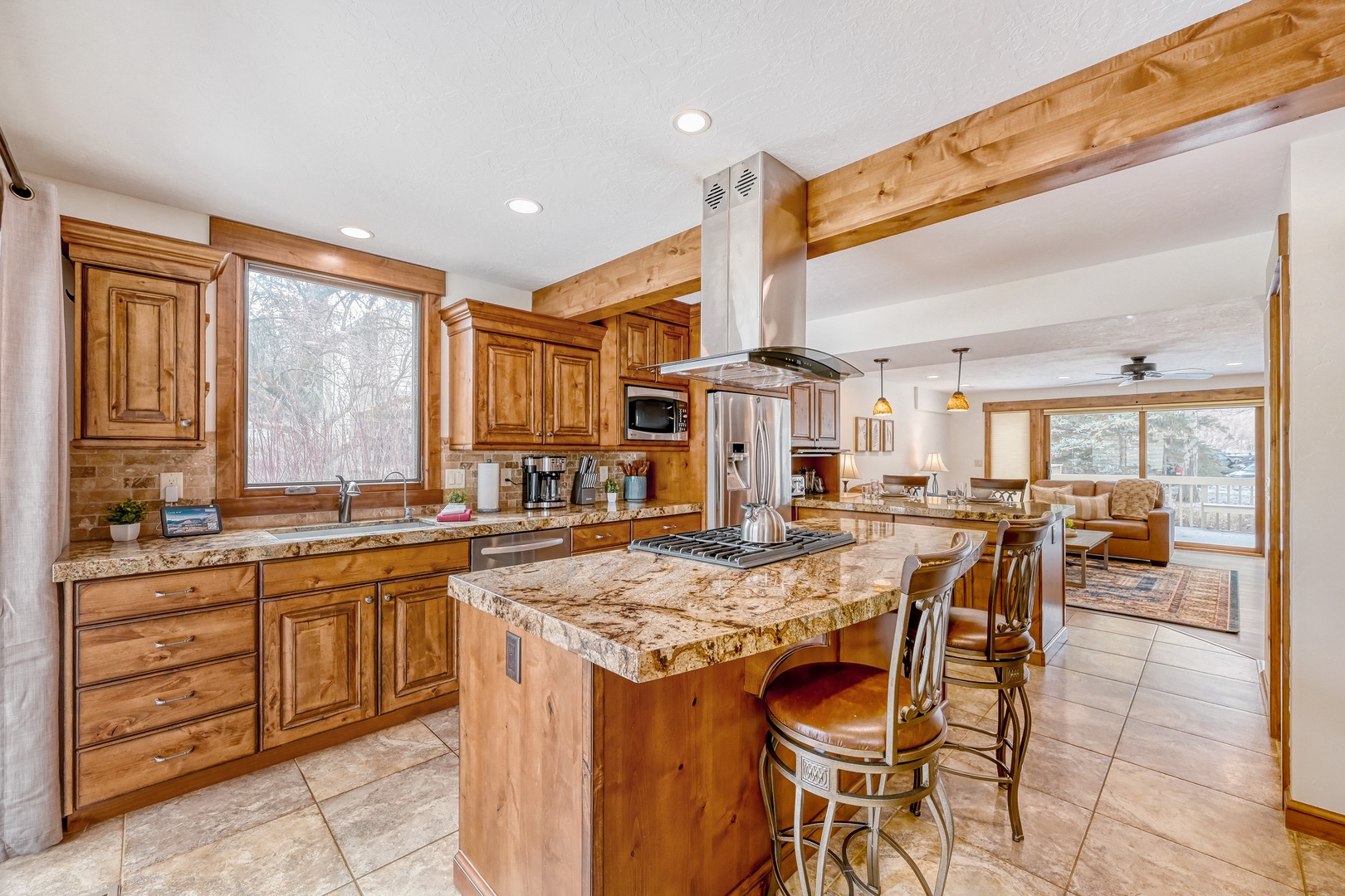 Gather around this stunning granite island where rustic wood beams meet modern appliances, creating your perfect mountain retreat cooking space.