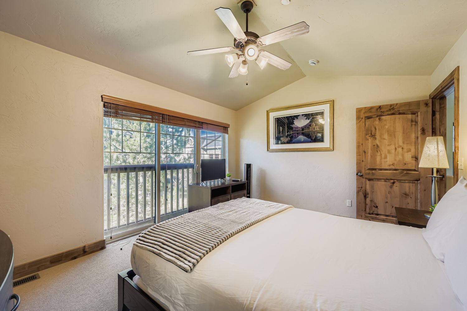 Relax in your peaceful bedroom with comfortable linens, ceiling fan, and lovely tree views through the large windows.
