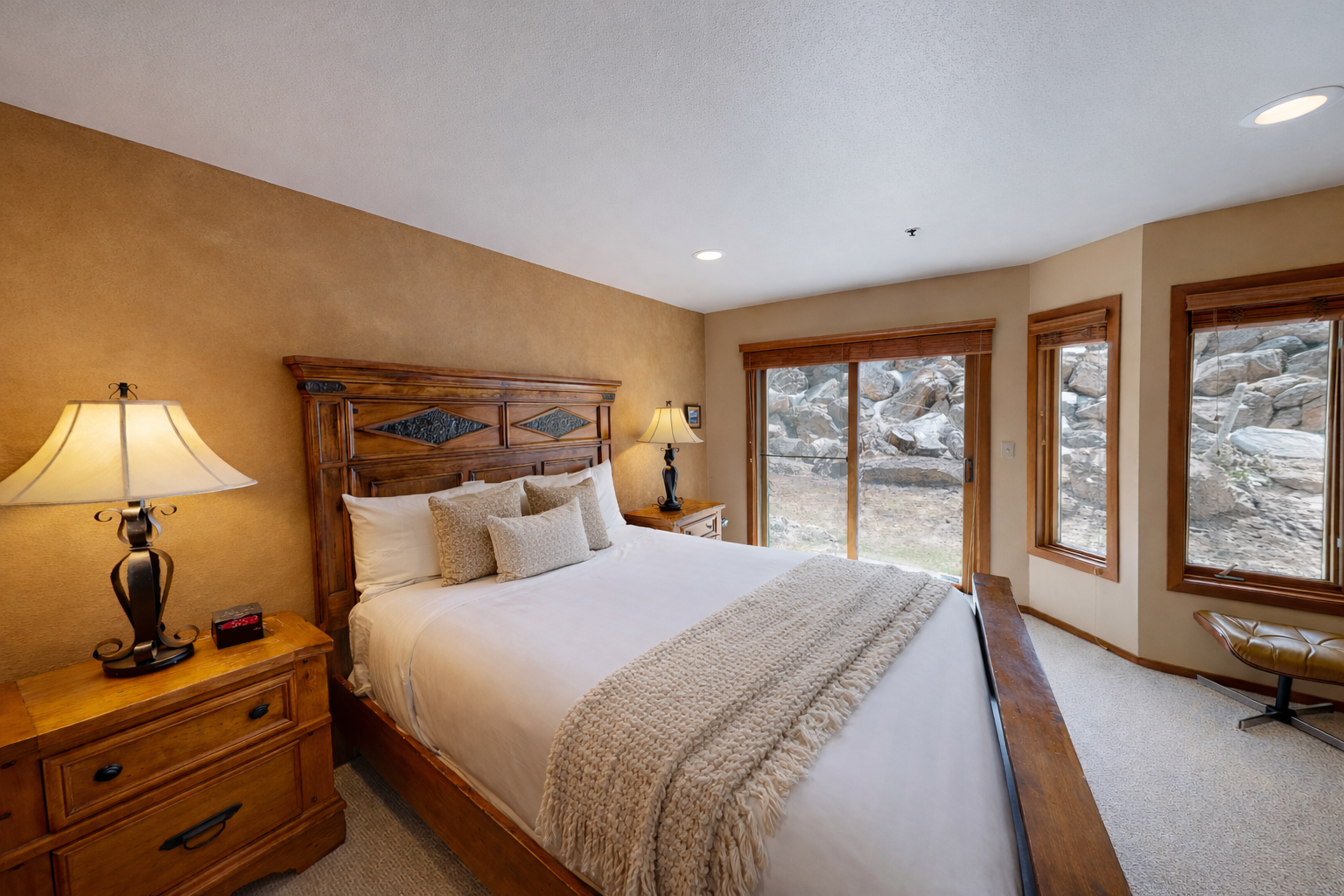 Drift off peacefully in your cozy bedroom overlooking a serene natural landscape through expansive windows.