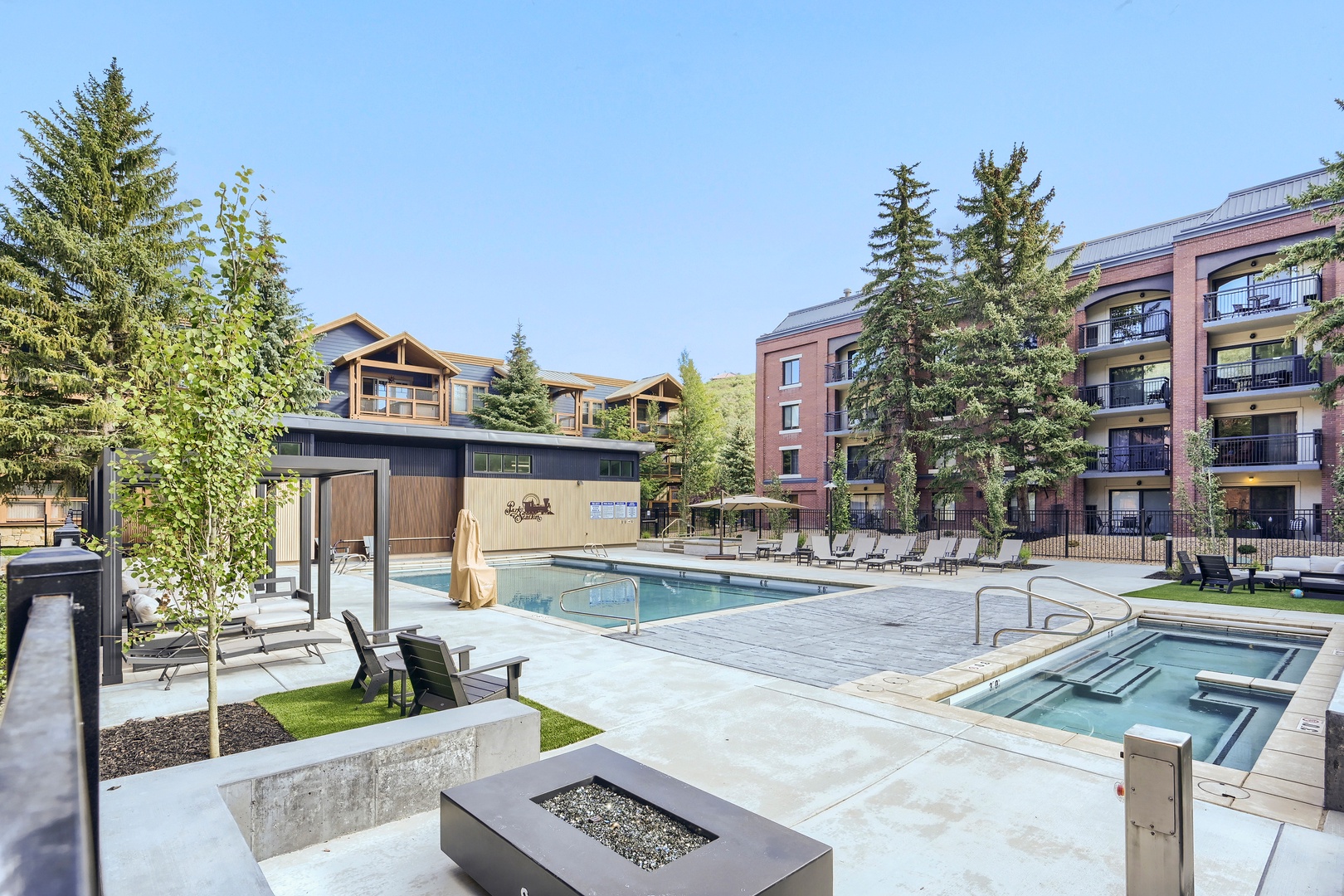 The property features beautifully landscaped grounds with multiple pools and relaxation areas surrounded by mature evergreens. Modern architecture blends mountain charm with upscale resort-style amenities perfect for your alpine getaway.