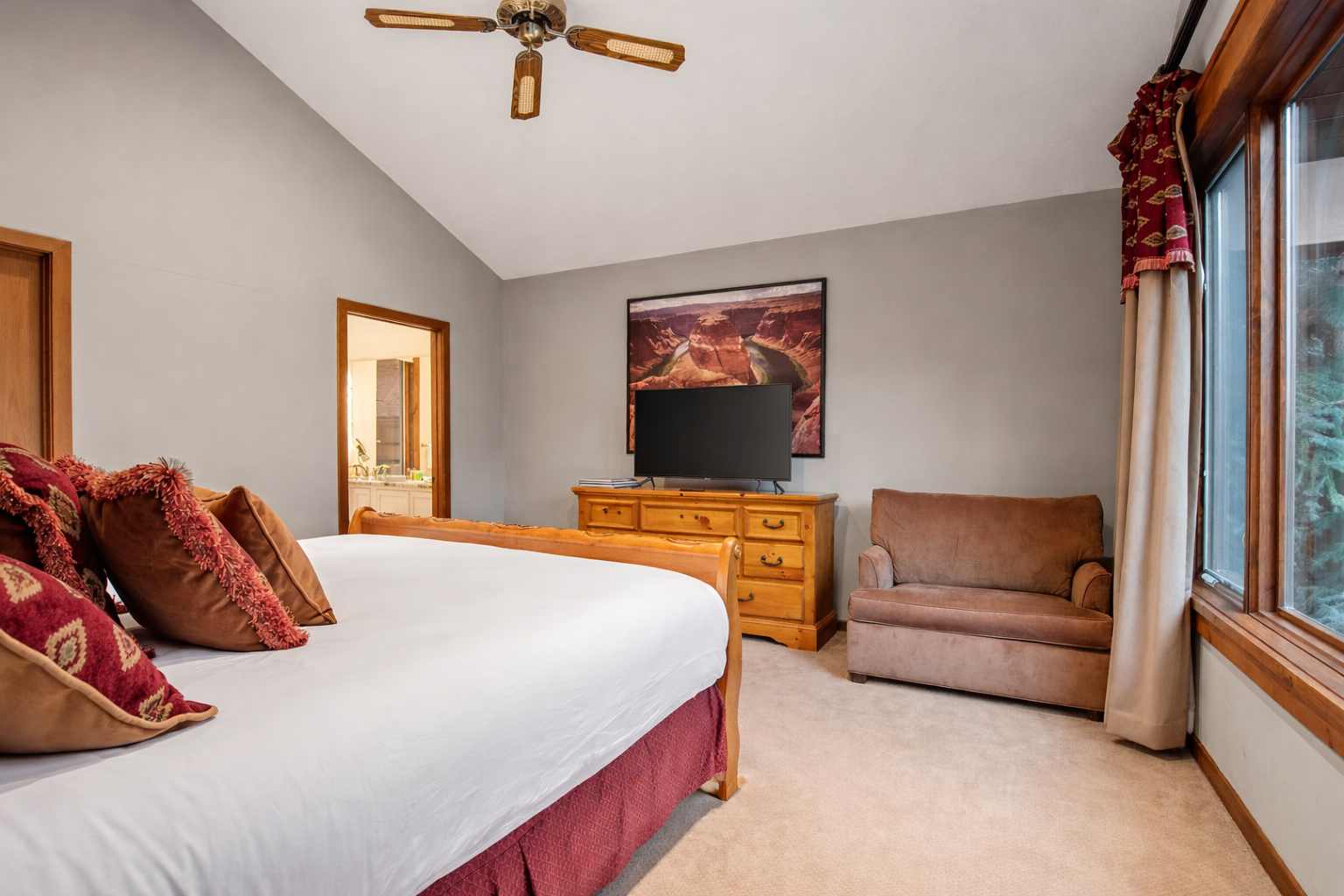 Your spacious bedroom combines comfort with mountain charm, featuring a plush bed, cozy reading chair, and entertainment center for perfect relaxation.