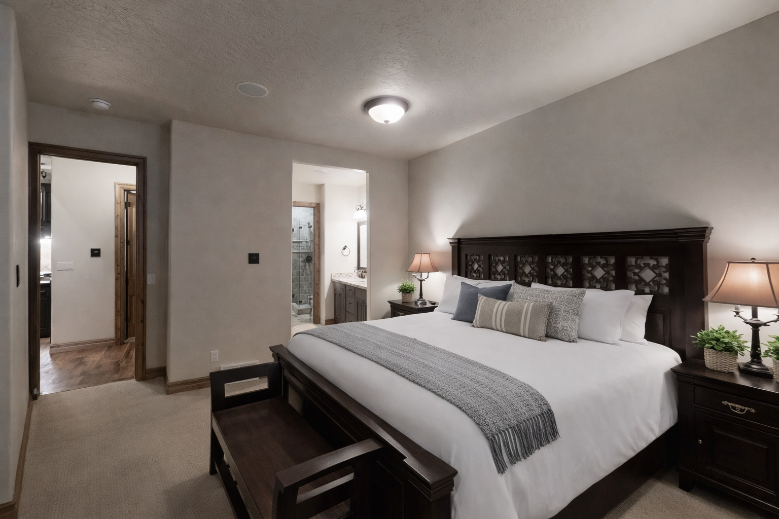 Unwind in this serene primary suite featuring a plush king bed, rich dark wood furnishings, and warm lighting. Large shuttered windows and soft neutral tones create a peaceful mountain sanctuary.