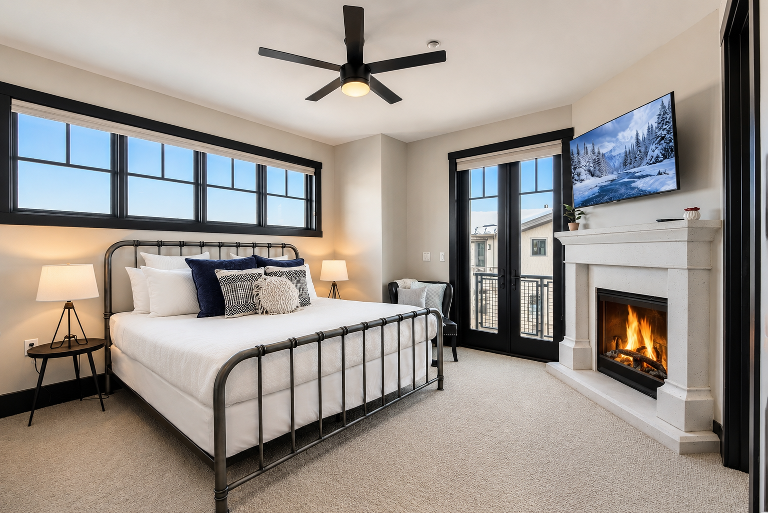 Relax in this bright master suite featuring a plush king bed and a cozy fireplace. Large windows and a private balcony offer serene views for a perfect mountain retreat.
