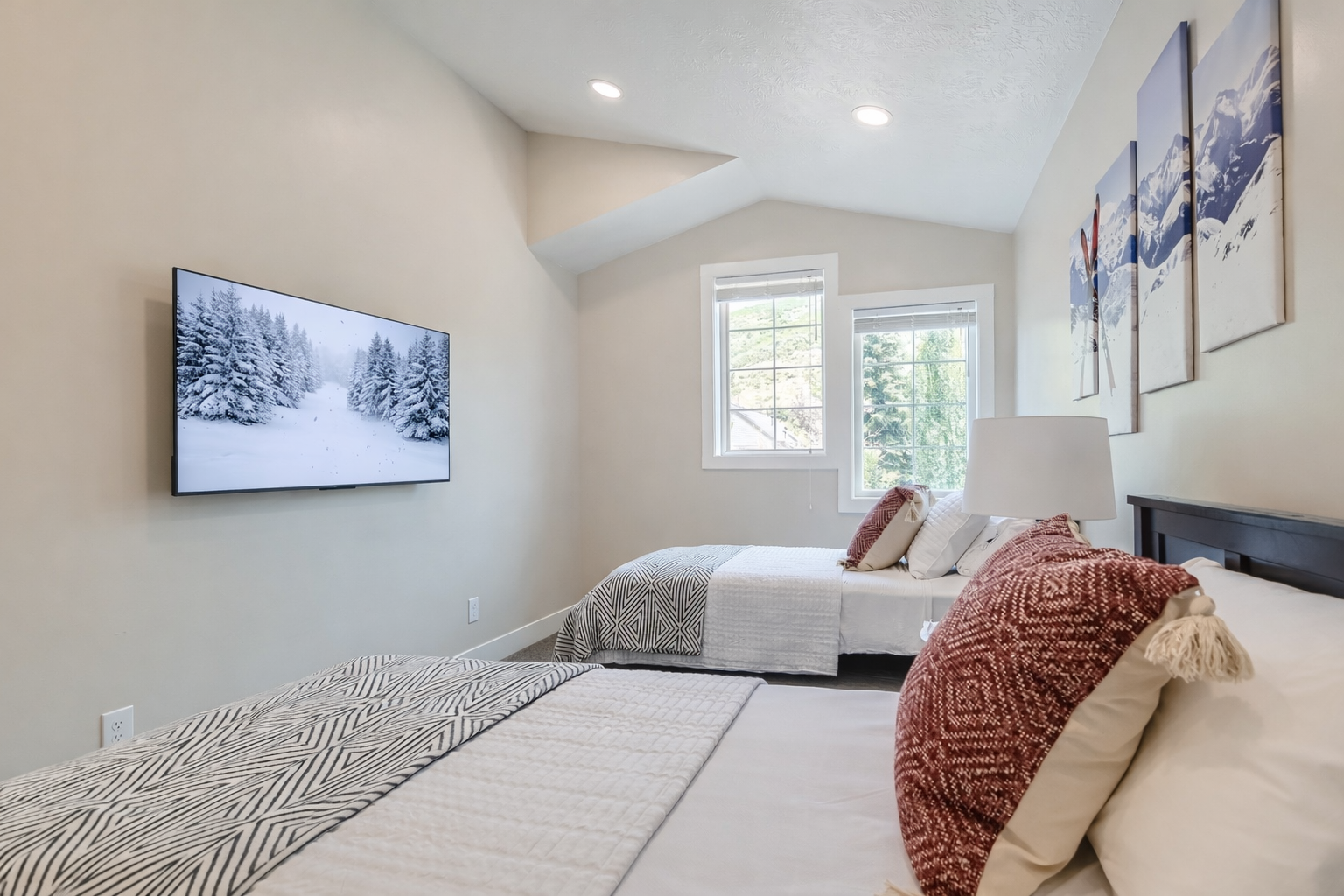 Relax in your cozy bedroom featuring twin beds, large TV, and mountain artwork creating a serene alpine atmosphere.