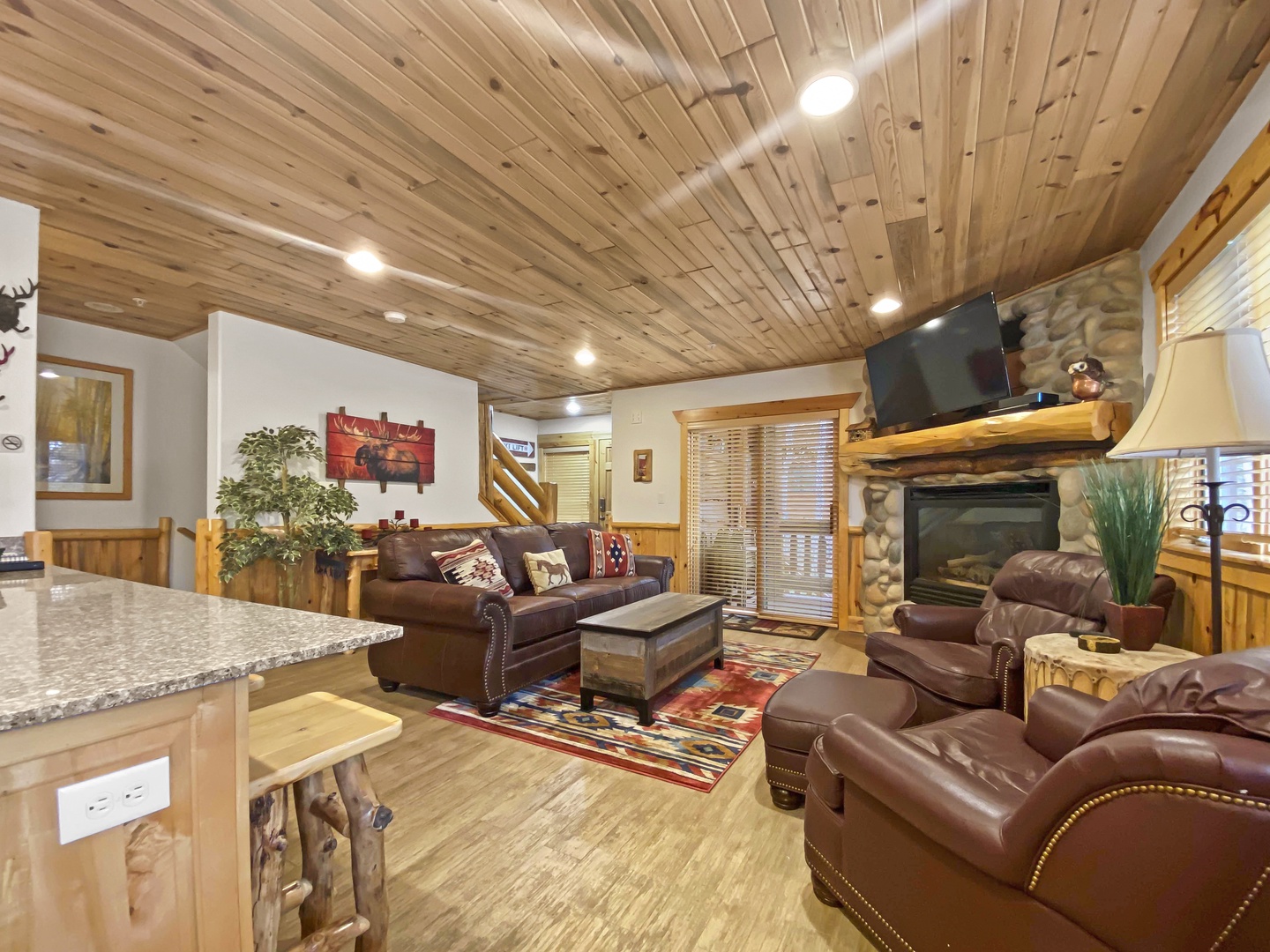 Sink into plush leather seating beneath soaring wood-plank ceilings as the stone fireplace warms your mountain retreat. The open layout invites relaxation after your day's adventures.