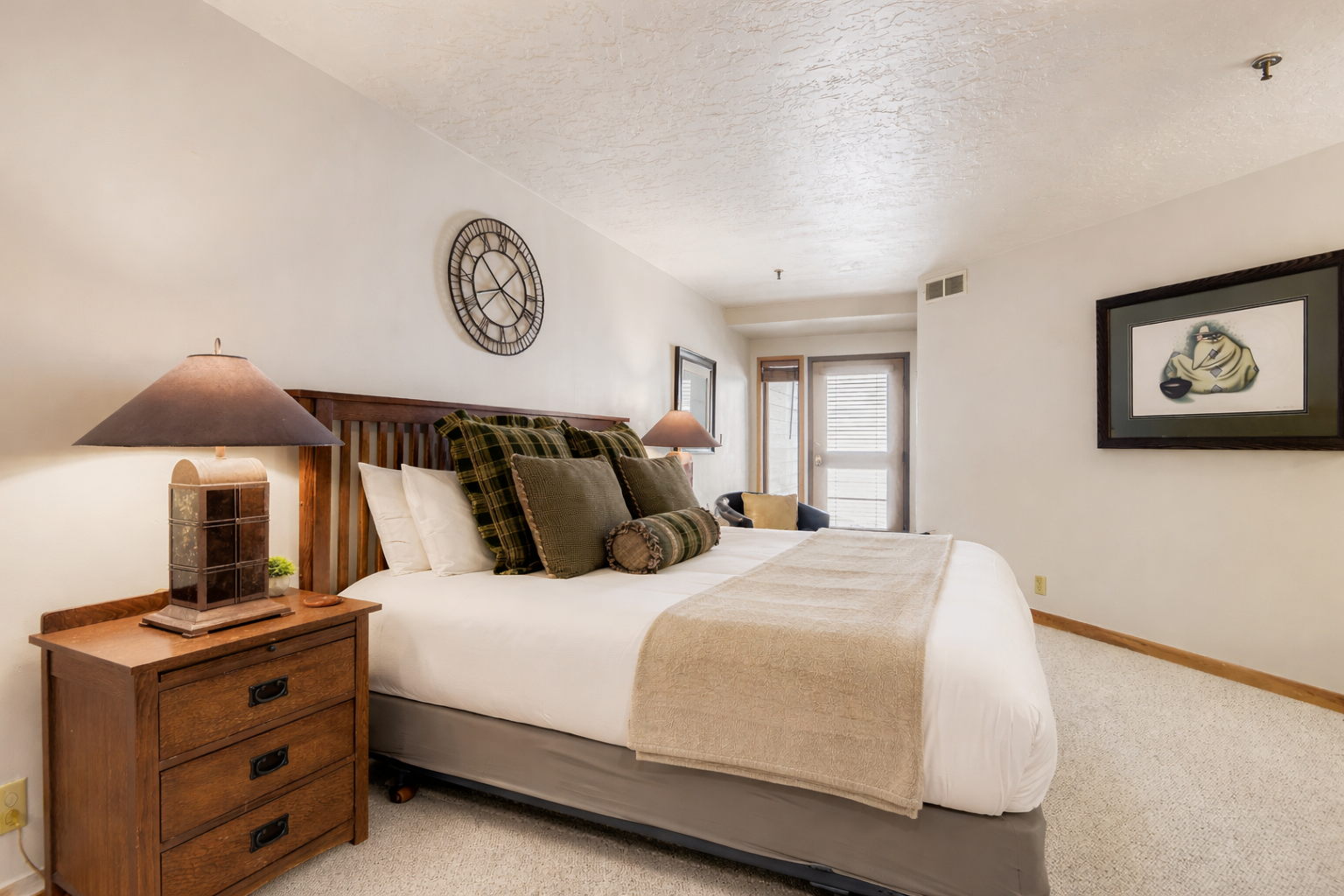 Retreat to this cozy bedroom featuring a comfortable queen bed and rustic wooden furniture. Enjoy the warm ambiance and peaceful setting for your Park City escape.