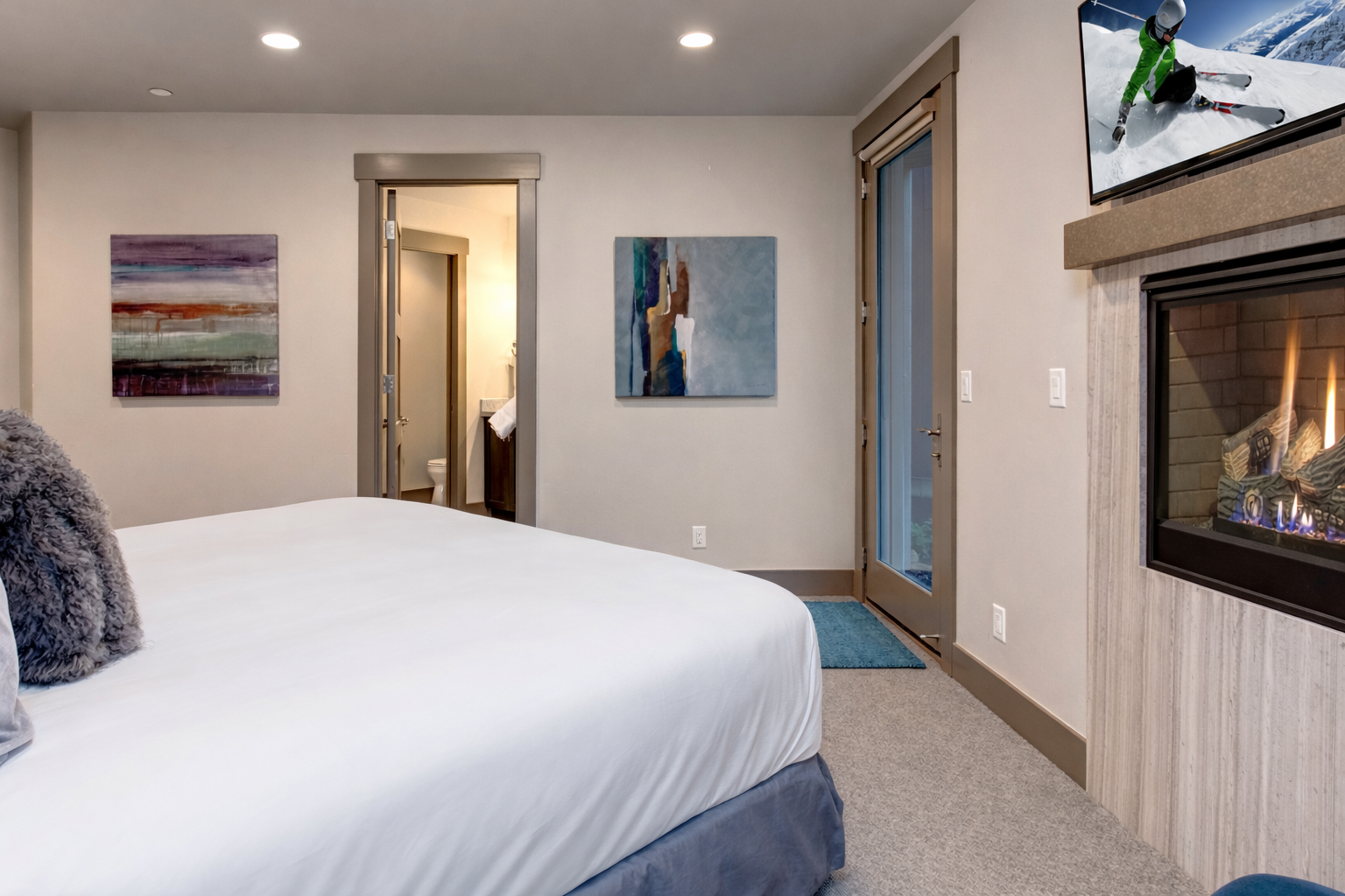 Unwind in your cozy bedroom with crisp linens, a warming fireplace, and modern amenities creating the perfect retreat after mountain adventures.