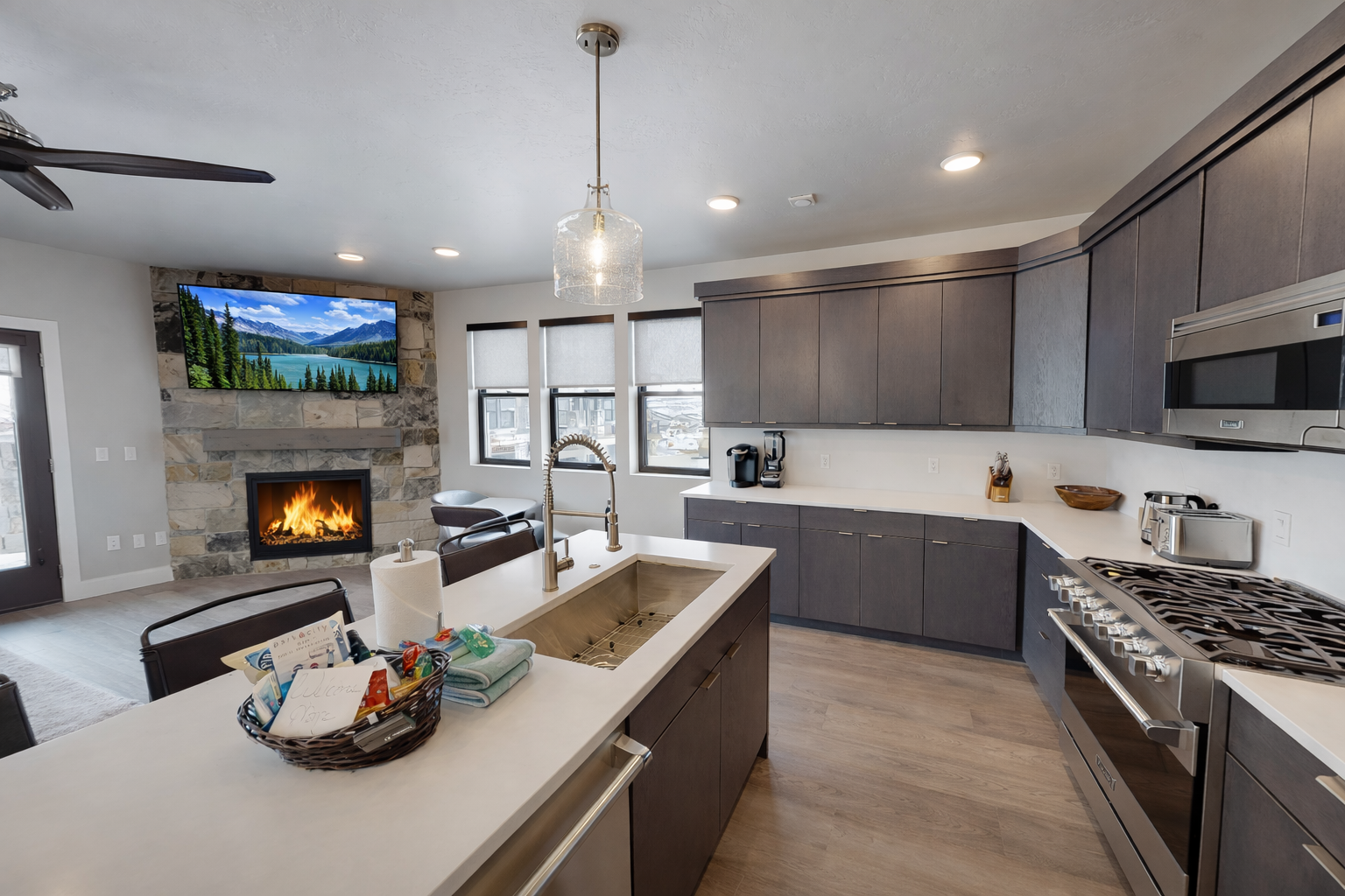 Enjoy this sleek, modern kitchen featuring a spacious island and high-end finishes. The open-concept design flows into a cozy living area with a warm stone fireplace, perfect for entertaining.