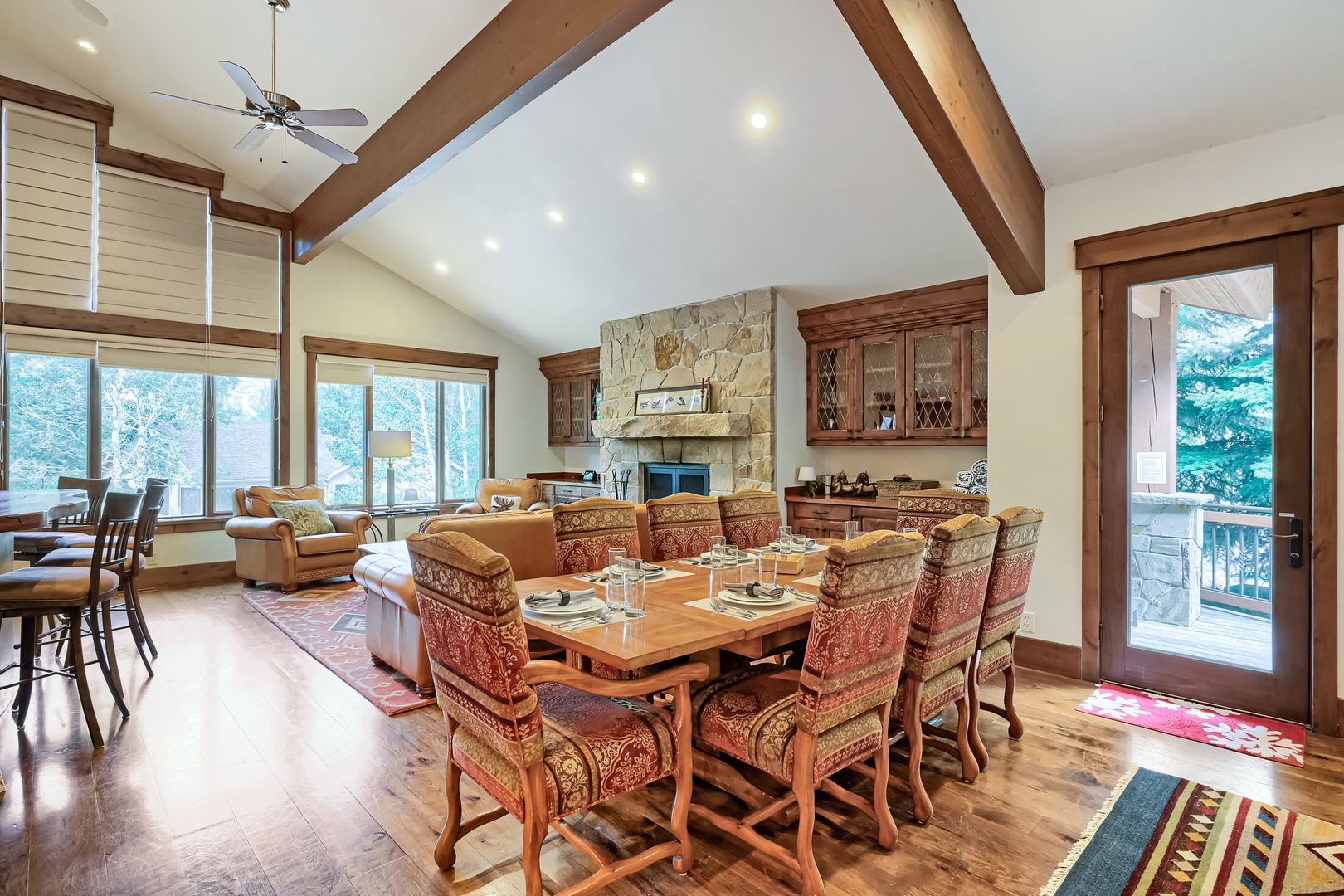 Spacious retreat featuring vaulted ceilings, warm wood beams, and large dining area. Relax by the stone fireplace with natural light from floor-to-ceiling windows.