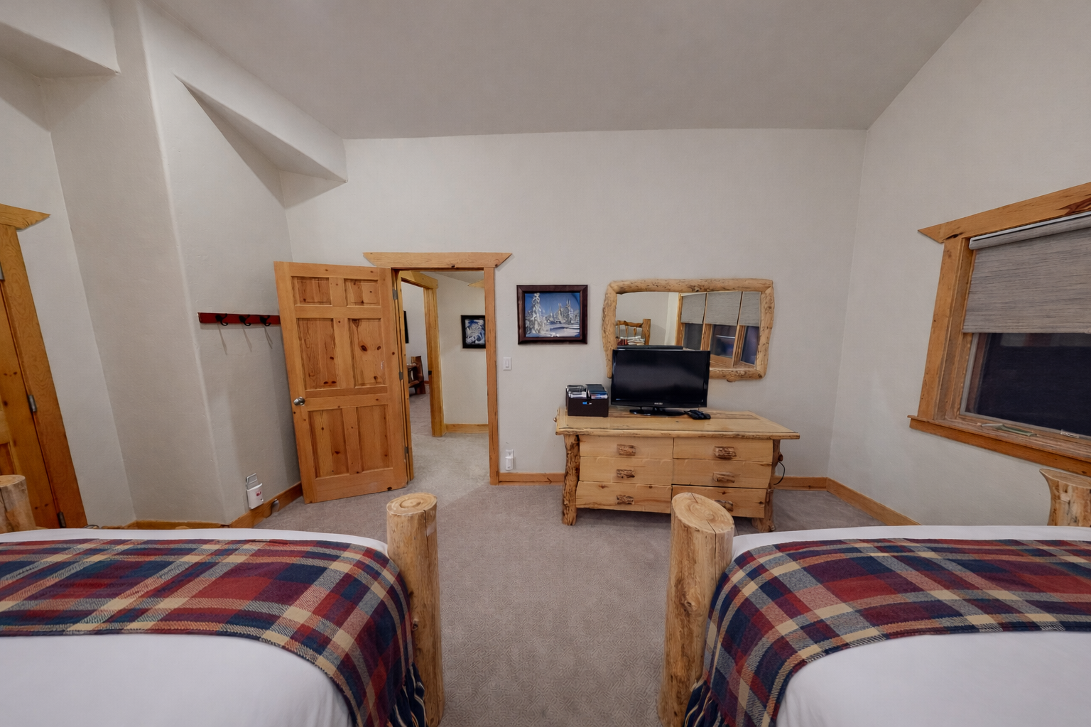 Your cozy mountain retreat features handcrafted log furniture, two plush beds with rustic plaid blankets, and a TV for unwinding after your adventures.