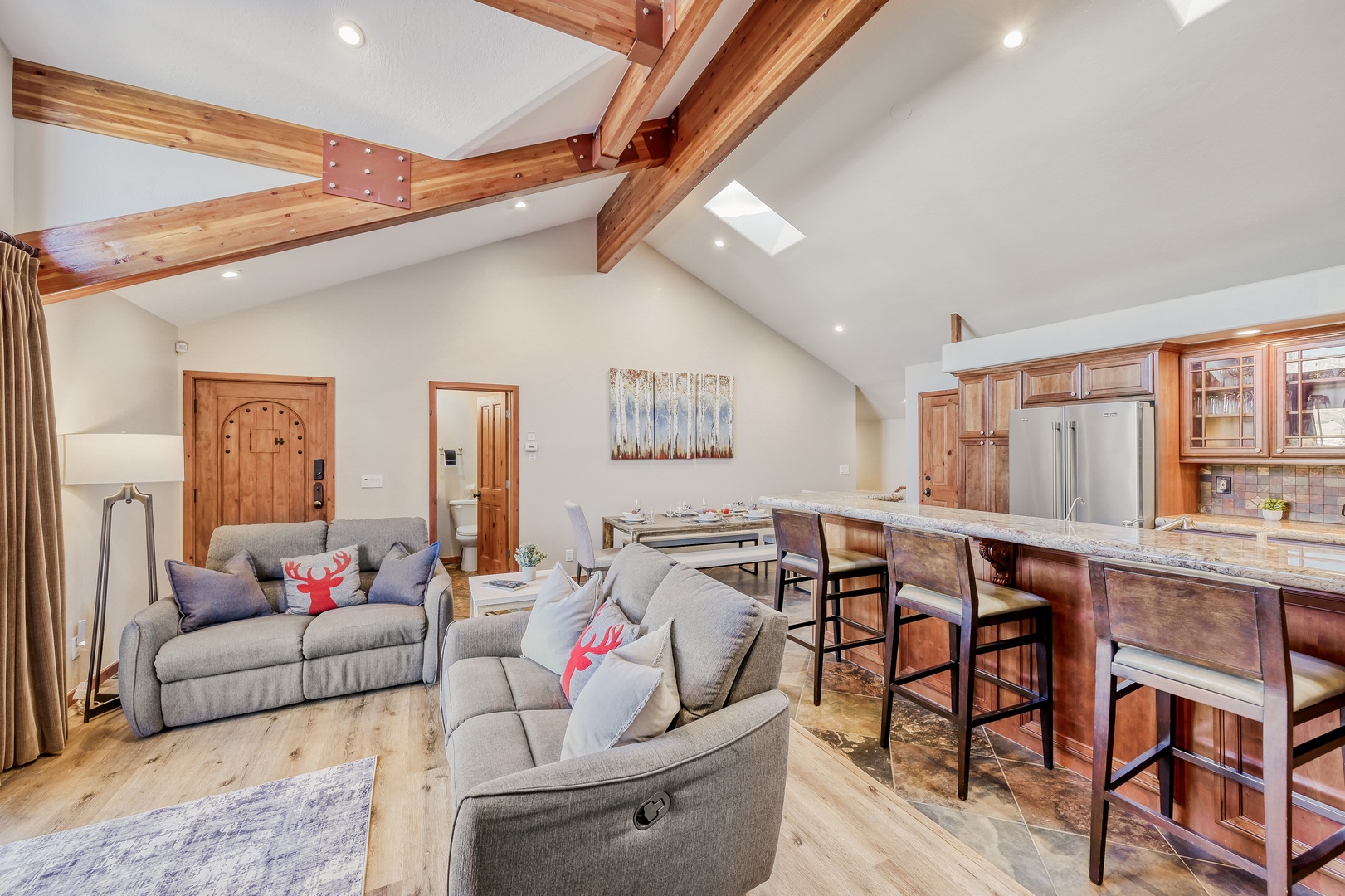 Relax in your open-concept living space featuring vaulted ceilings with exposed beams, a fully equipped kitchen, and cozy seating area.