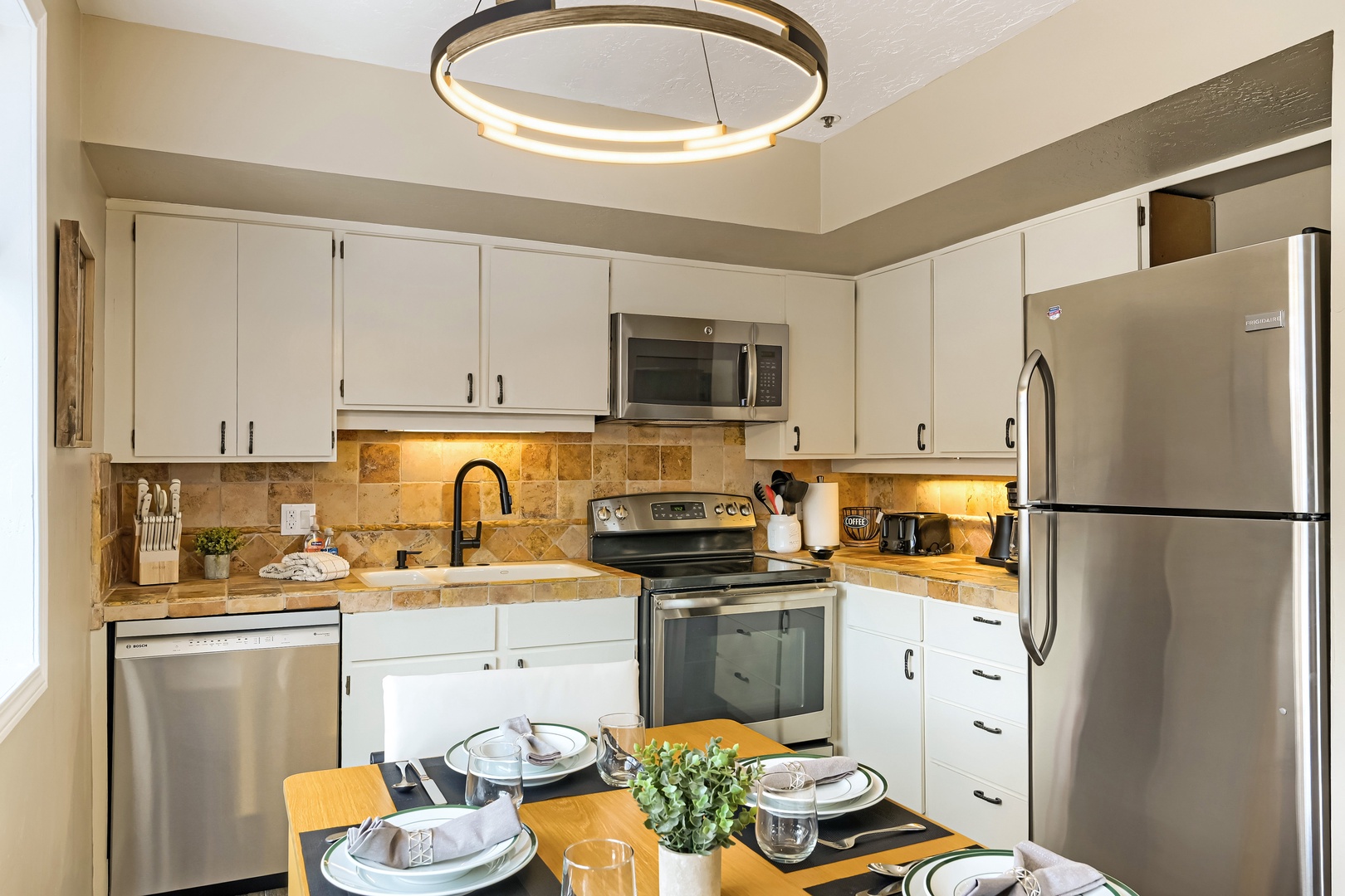 Your fully equipped kitchen invites you to cook and gather, with stainless appliances, warm tile backsplash, and a dining table ready for morning coffee or shared meals.