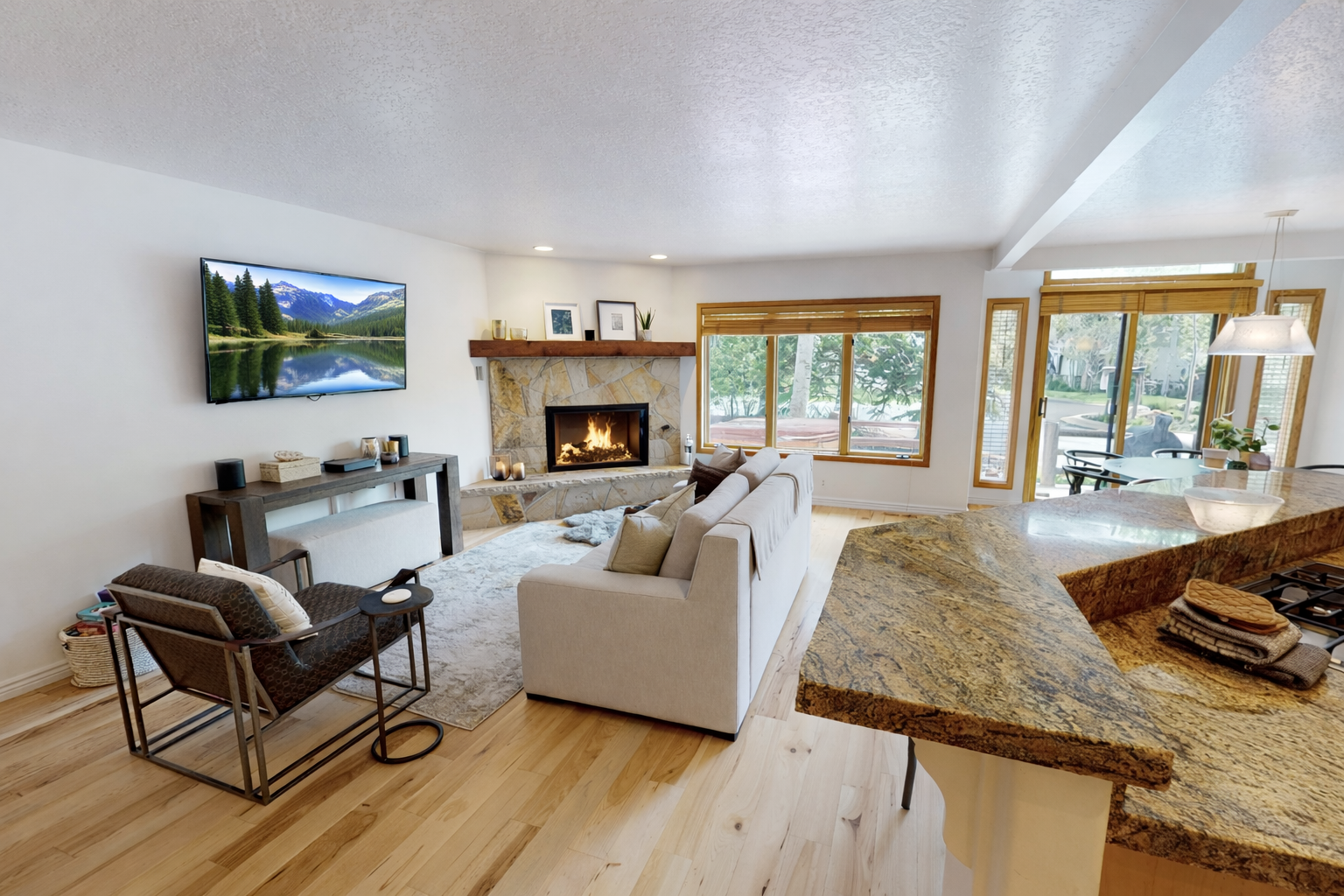 This spacious living room features a cozy fireplace and large windows offering scenic mountain views. Relax on the comfortable sectional while enjoying the tranquil atmosphere.