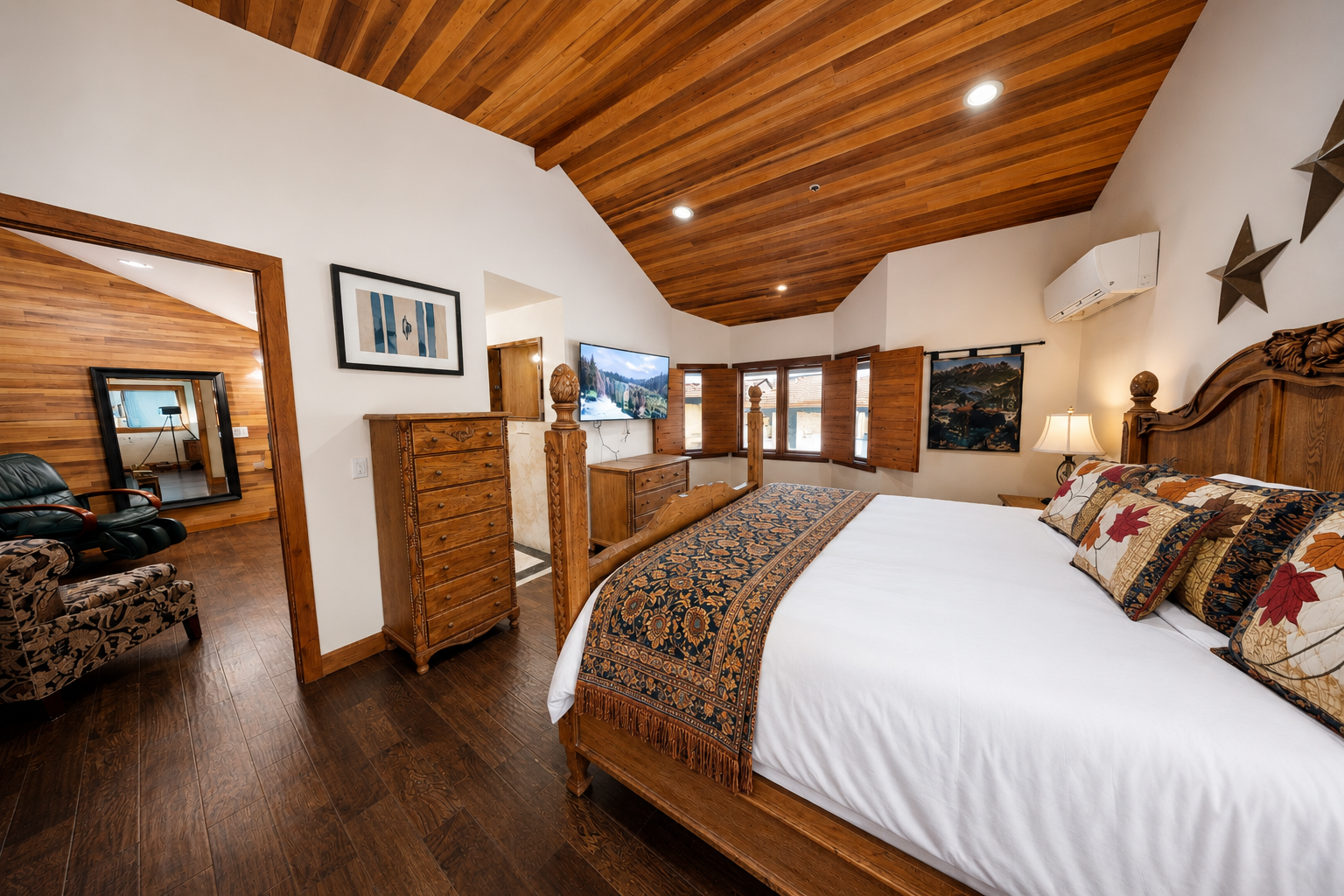 Relax under dramatic wood-beam ceilings in your spacious bedroom, featuring a king bed, cozy seating, and handcrafted furnishings. Mountain views through the windows invite natural light and peaceful moments.