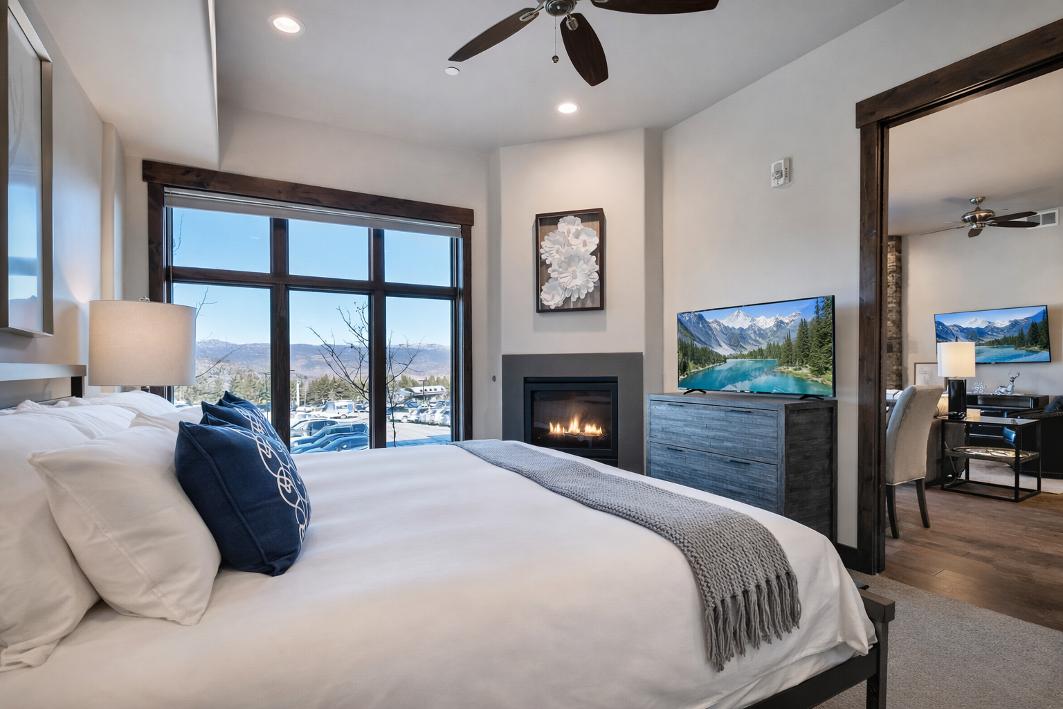 Unwind in your luxurious bedroom featuring a cozy fireplace, mountain views, and modern TV for the perfect alpine retreat experience.