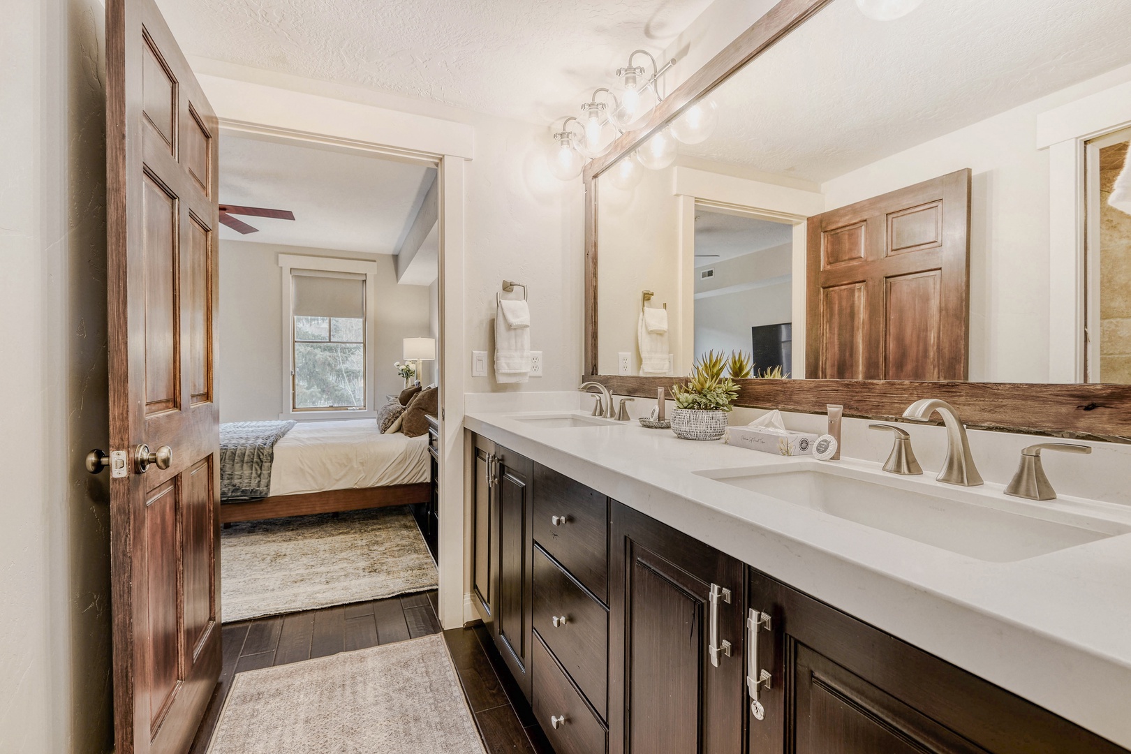 Step into your luxurious ensuite bathroom featuring dual vanities, elegant lighting, and a cozy connected bedroom for complete privacy and comfort.