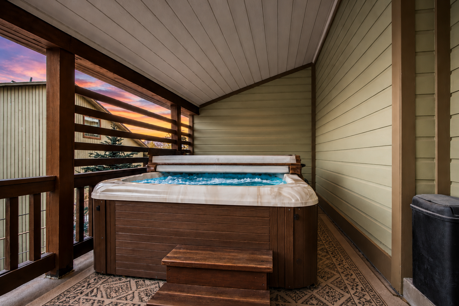 Unwind in your private hot tub on the covered balcony as the sun sets, painting the sky in soft hues just beyond the trees.