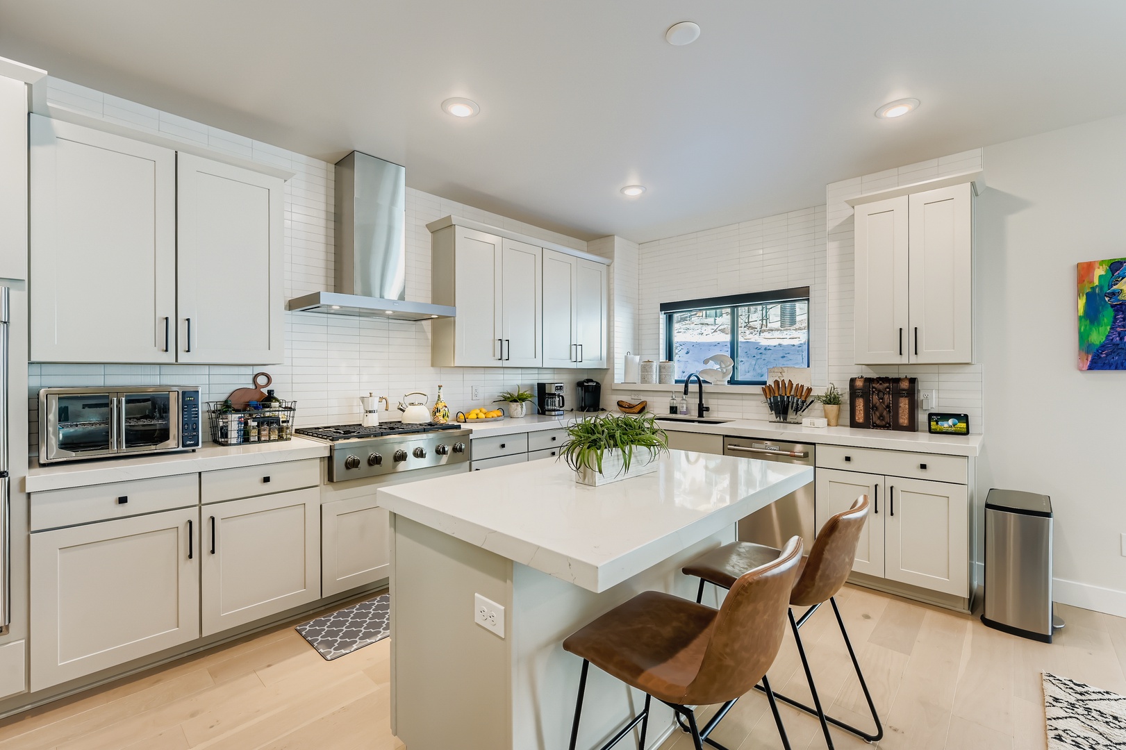 Step into your bright, spacious kitchen with gleaming white cabinetry, a welcoming island, and modern appliances ready for preparing meals together during your stay.