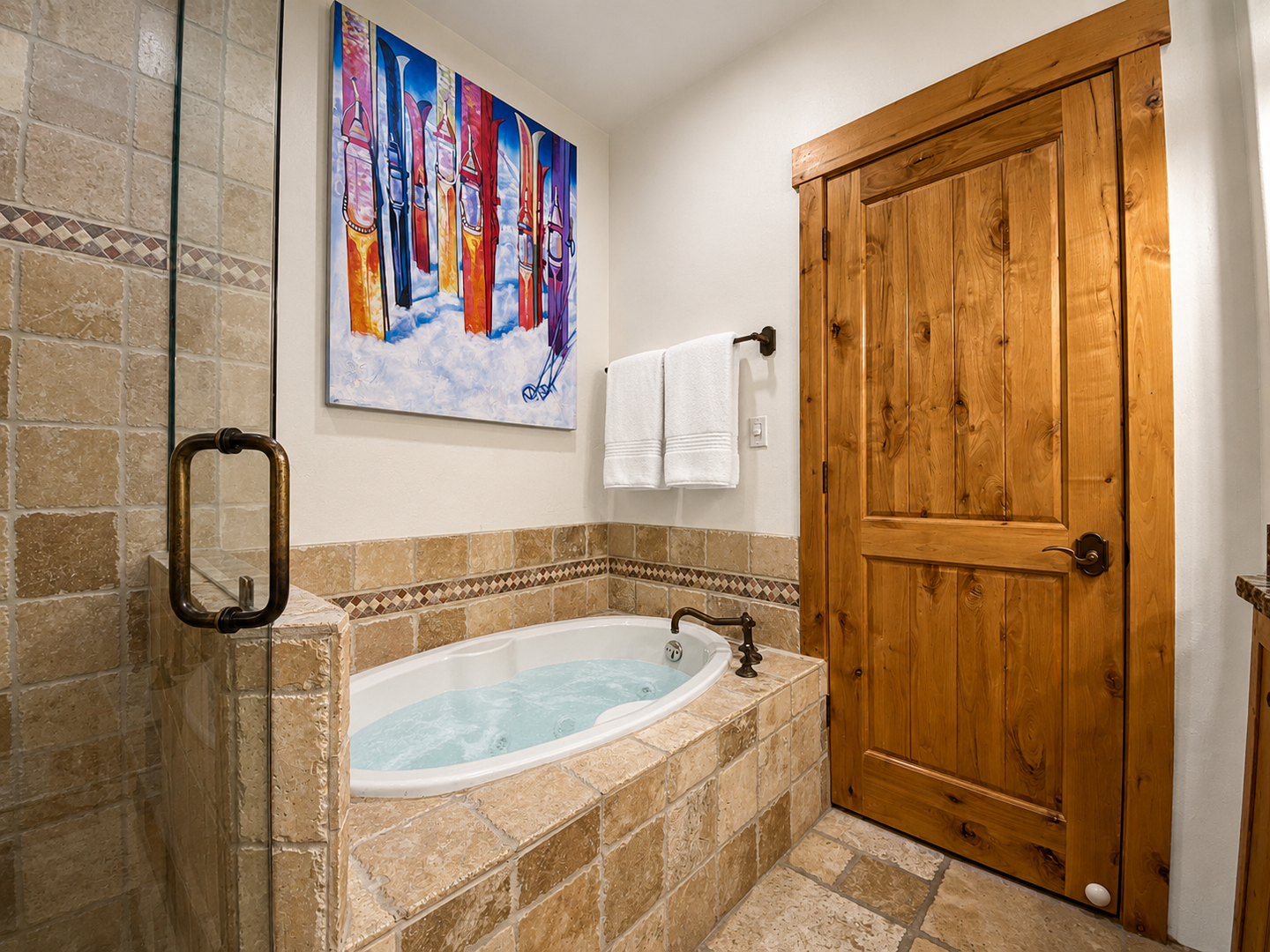 Unwind in this charming bathroom featuring a spacious jetted tub and elegant tile surround. The warm, knotty wood door adds a cozy, rustic touch to your relaxing retreat.