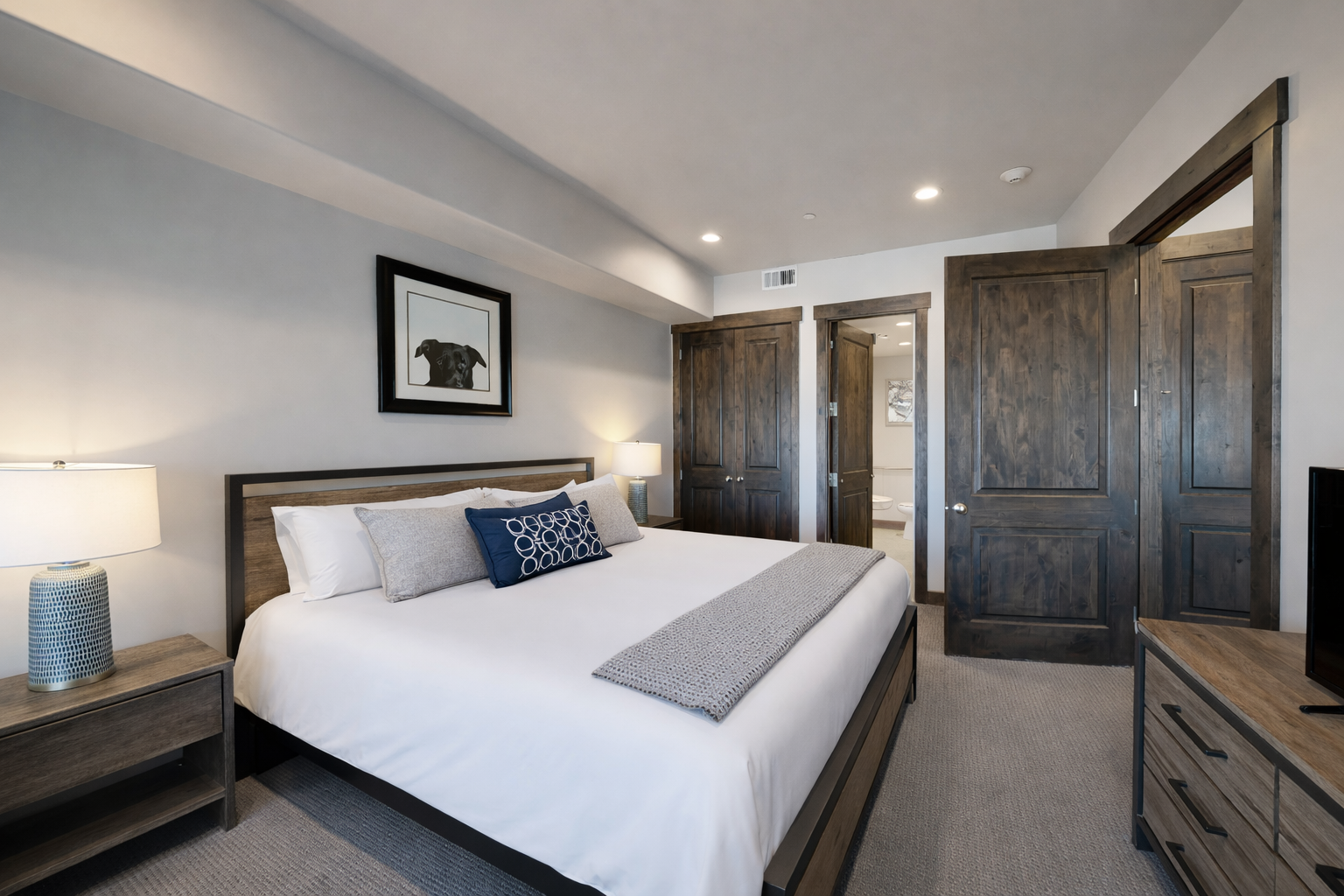 Sink into crisp white linens and rest your head on plush pillows in this modern bedroom featuring rustic wood accents.