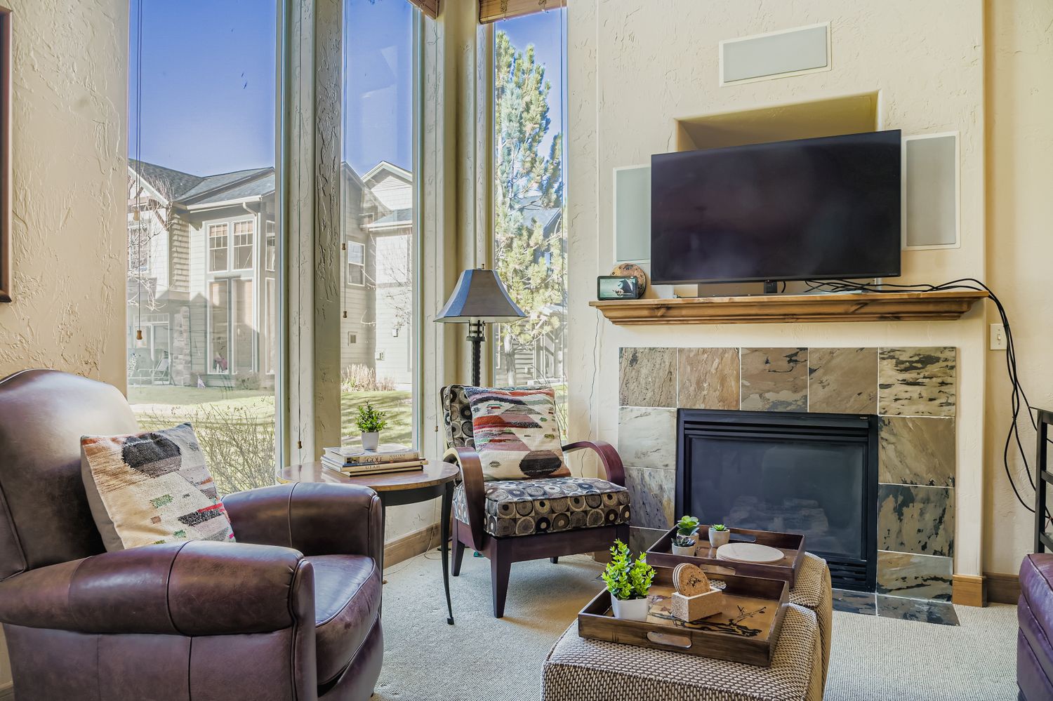 Settle into this cozy living room with comfortable leather seating, a warm fireplace, and large windows that fill the space with natural light for your perfect relaxation time.