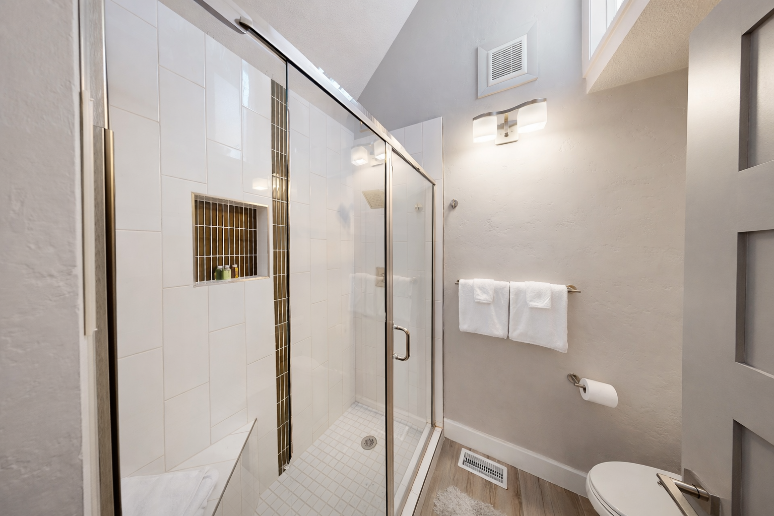 Sparkling clean and functional, this ensuite bathroom offers a large glass shower and built-in wall niche for toiletries. Enjoy a serene, spa-like atmosphere in a compact, stylish design.