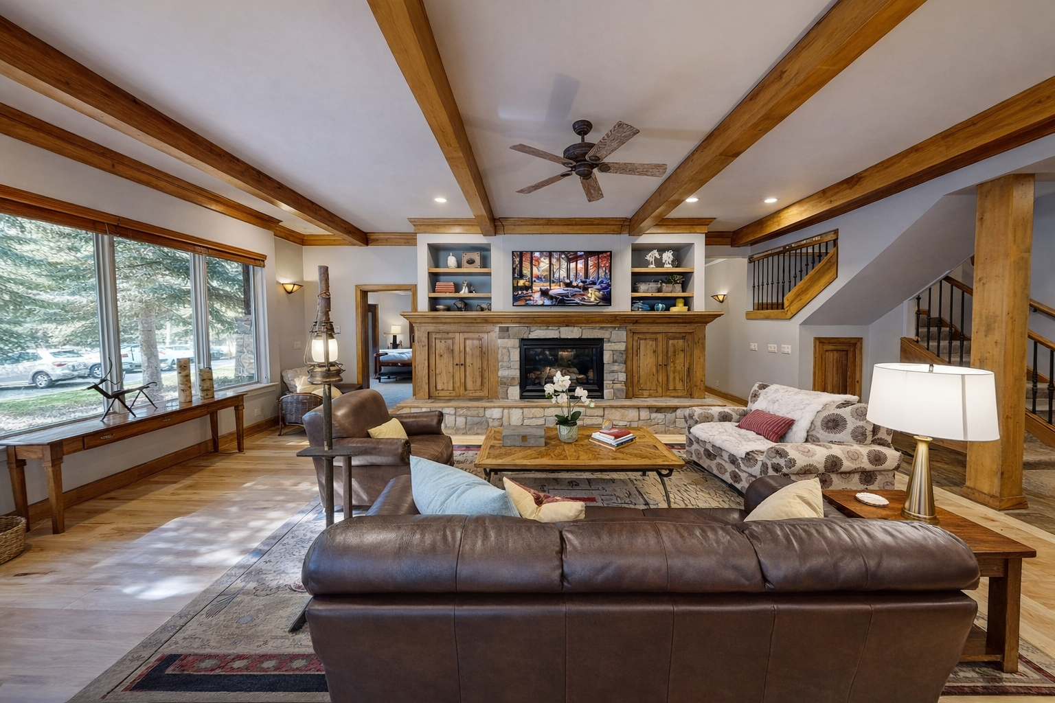 Unwind in this stunning great room with exposed beams, stone fireplace, and plush leather seating where cozy mountain evenings await.