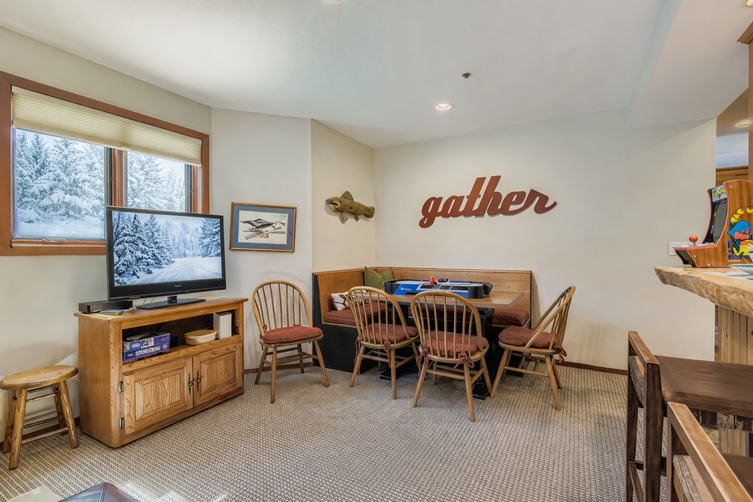 Your cozy dining nook invites family meals with rustic charm, featuring warm wood furnishings and snowy mountain views through the window.