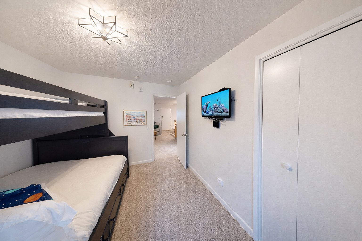 Unwind in your cozy bunk room featuring modern amenities, wall-mounted TV for entertainment, and stylish star-shaped lighting overhead.