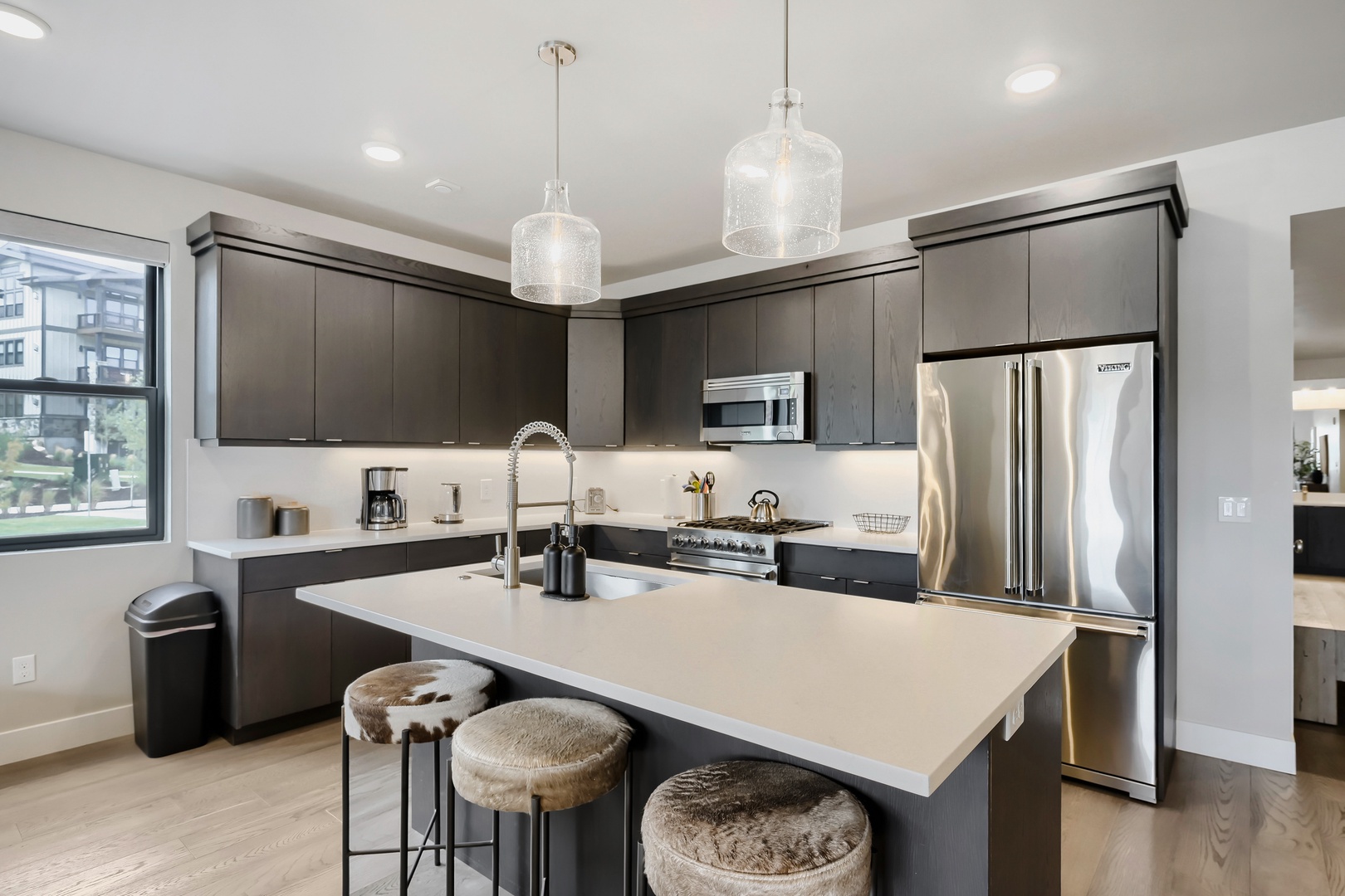 Step into your modern chef's kitchen featuring sleek dark cabinetry, gleaming stainless appliances, and a spacious island perfect for morning coffee or meal prep.