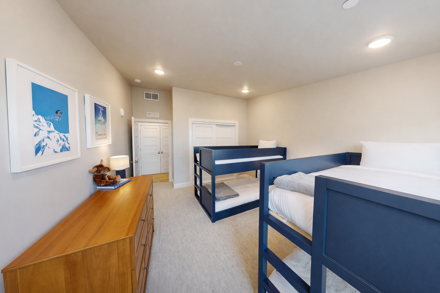 Perfect for kids or groups, this modern bunk room features sleek gray beds and a cozy blue gingham rug. Large windows offer bright, natural light and peaceful mountain views.