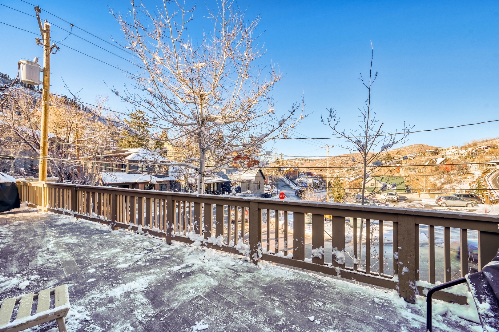 Winter mountain community view from a snow-dusted wooden deck overlooking the neighborhood below.