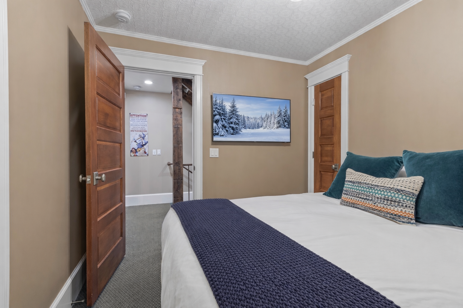 Cozy bedroom with plush teal pillows and warm mountain vibes displayed on your wall-mounted TV.