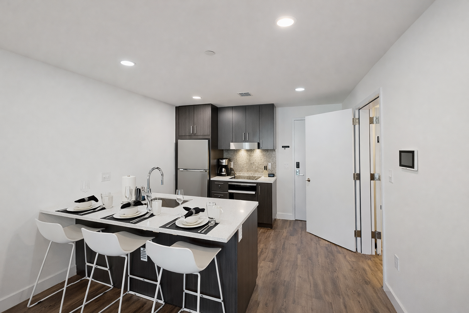 Enjoy this fully equipped kitchen featuring sleek quartz countertops and a spacious island with modern seating. Prepare meals with ease using the stainless steel appliances during your stay.
