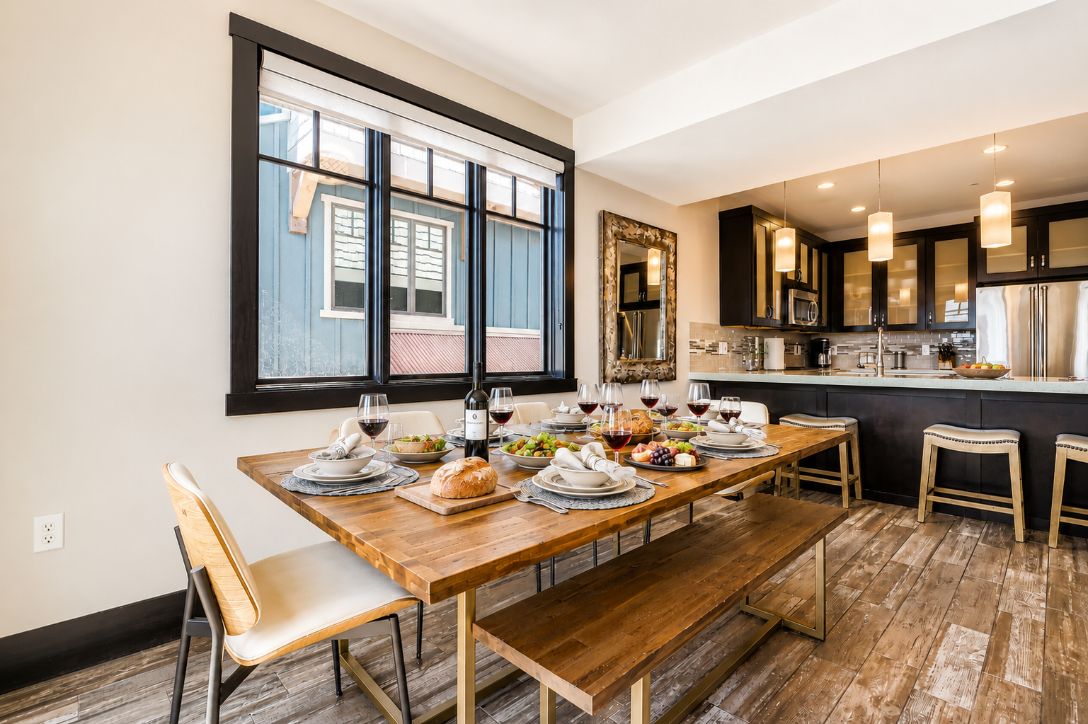 Gather around this inviting dining table where your group can share meals, laughter, and memories. Natural light pours through large windows, while the sleek kitchen waits nearby for your culinary adventures.