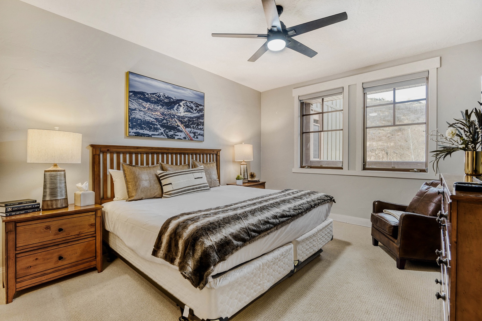 Unwind in your cozy bedroom featuring a plush queen bed, warm wood furnishings, and mountain views from your windows.