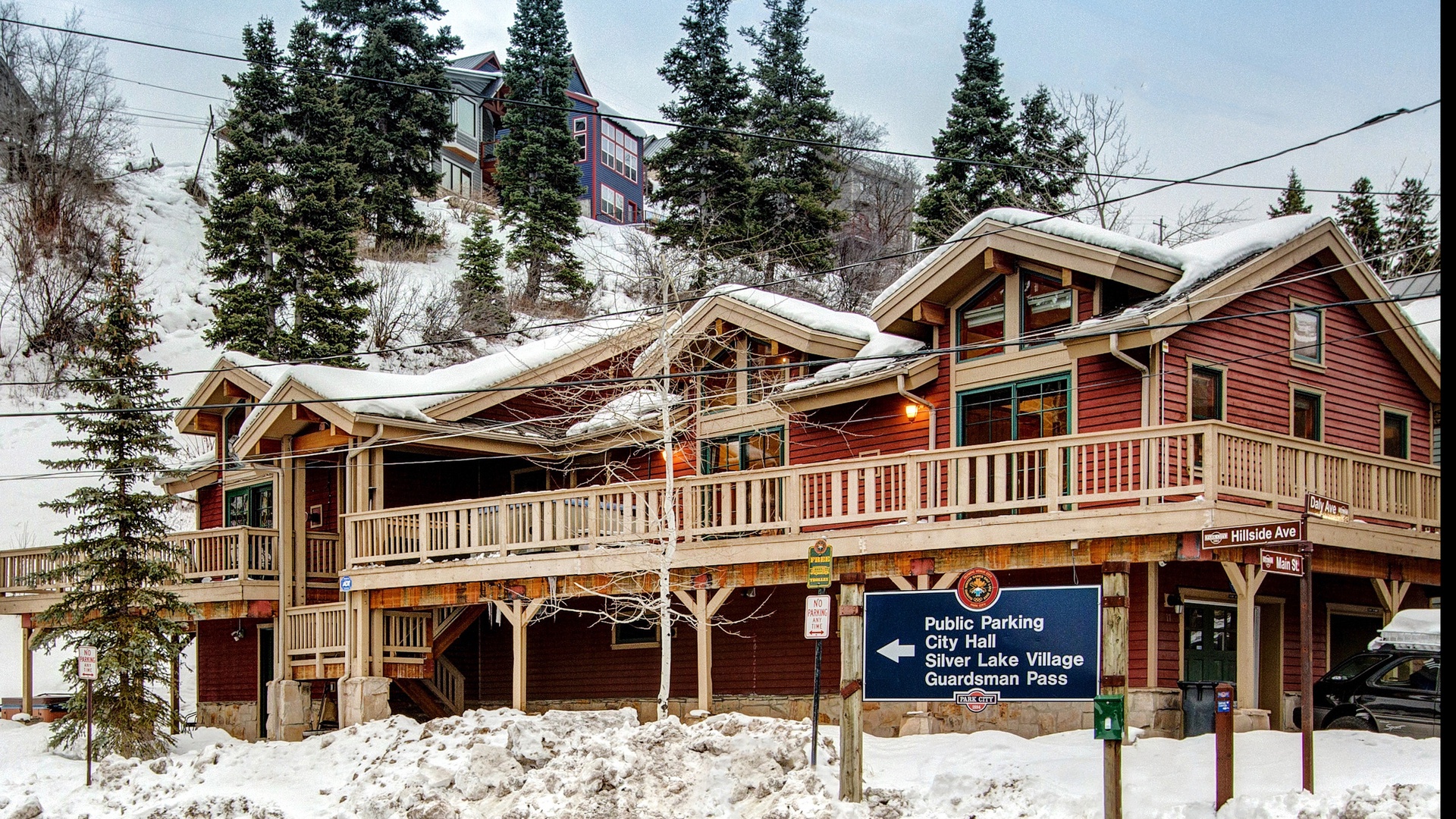 Charming mountain lodge with snow-covered balconies and rustic timber architecture nestled in a winter wonderland setting.
