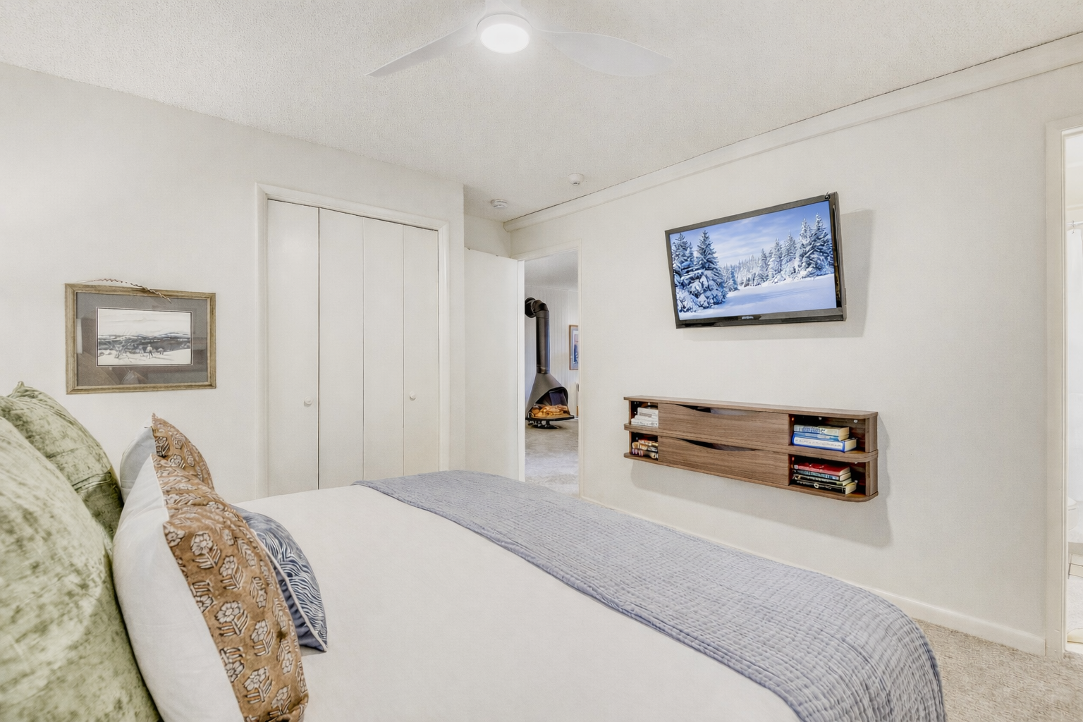 Unwind in your serene bedroom where clean lines meet cozy comfort, complete with entertainment center and peaceful mountain views on the wall-mounted TV.