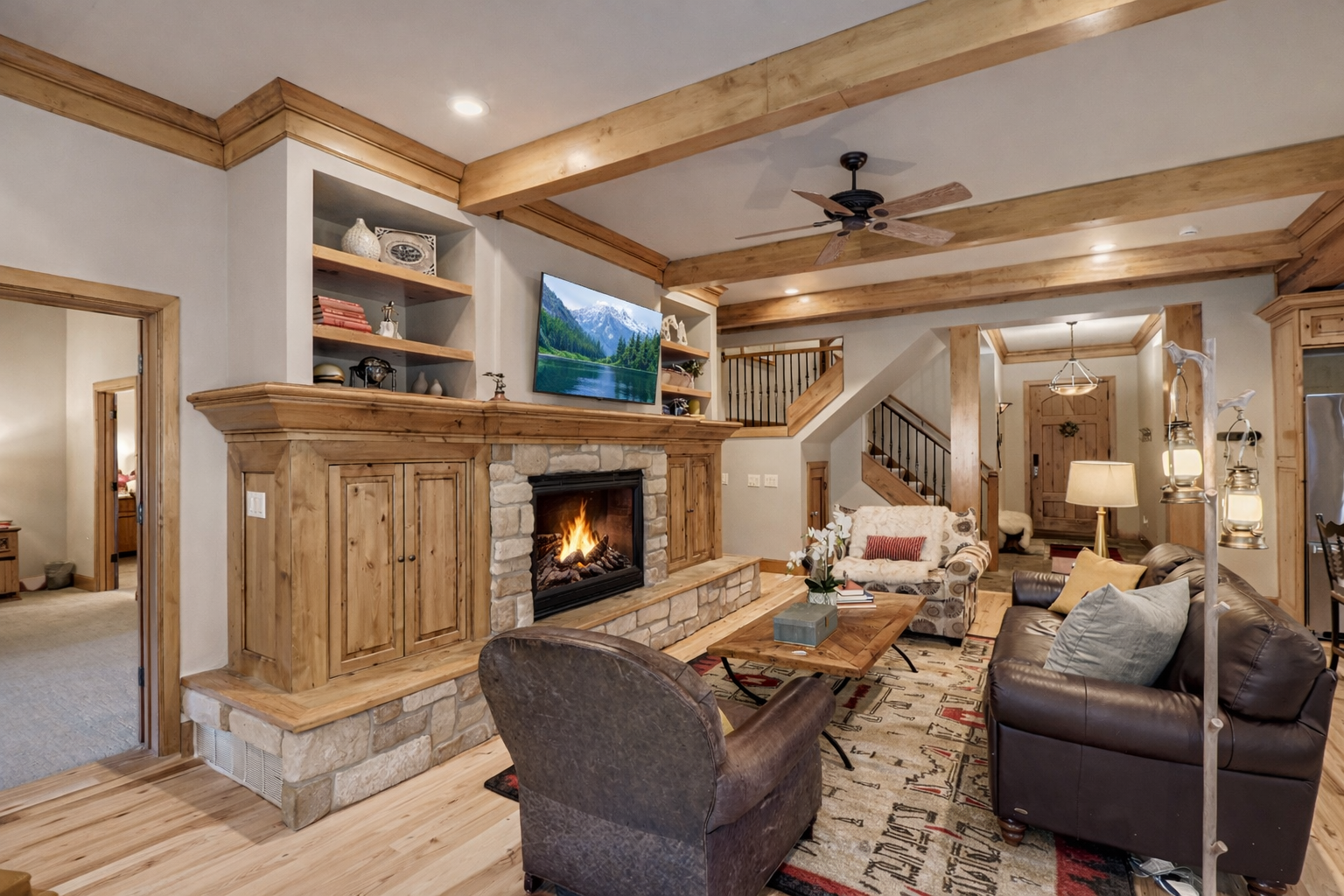 Escape to a cozy, rustic retreat! Enjoy this charming mountain living room featuring a stone fireplace, natural wood beams, and comfortable seating perfect for relaxation.