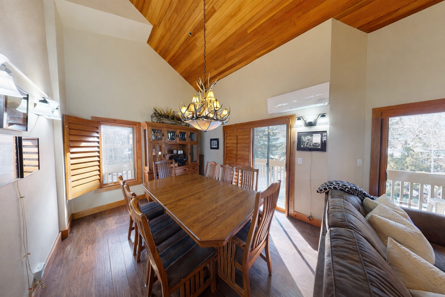 Gather around this inviting dining table beneath soaring wood-beam ceilings, where natural light pours through generous windows that frame stunning mountain views.