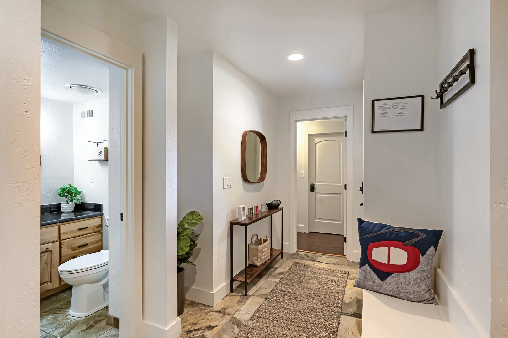 Step into your welcoming entry space, where thoughtful details invite you to settle in. A cozy bench greets you at the door, and just beyond, your private bathroom awaits with warm wood tones and natural touches.