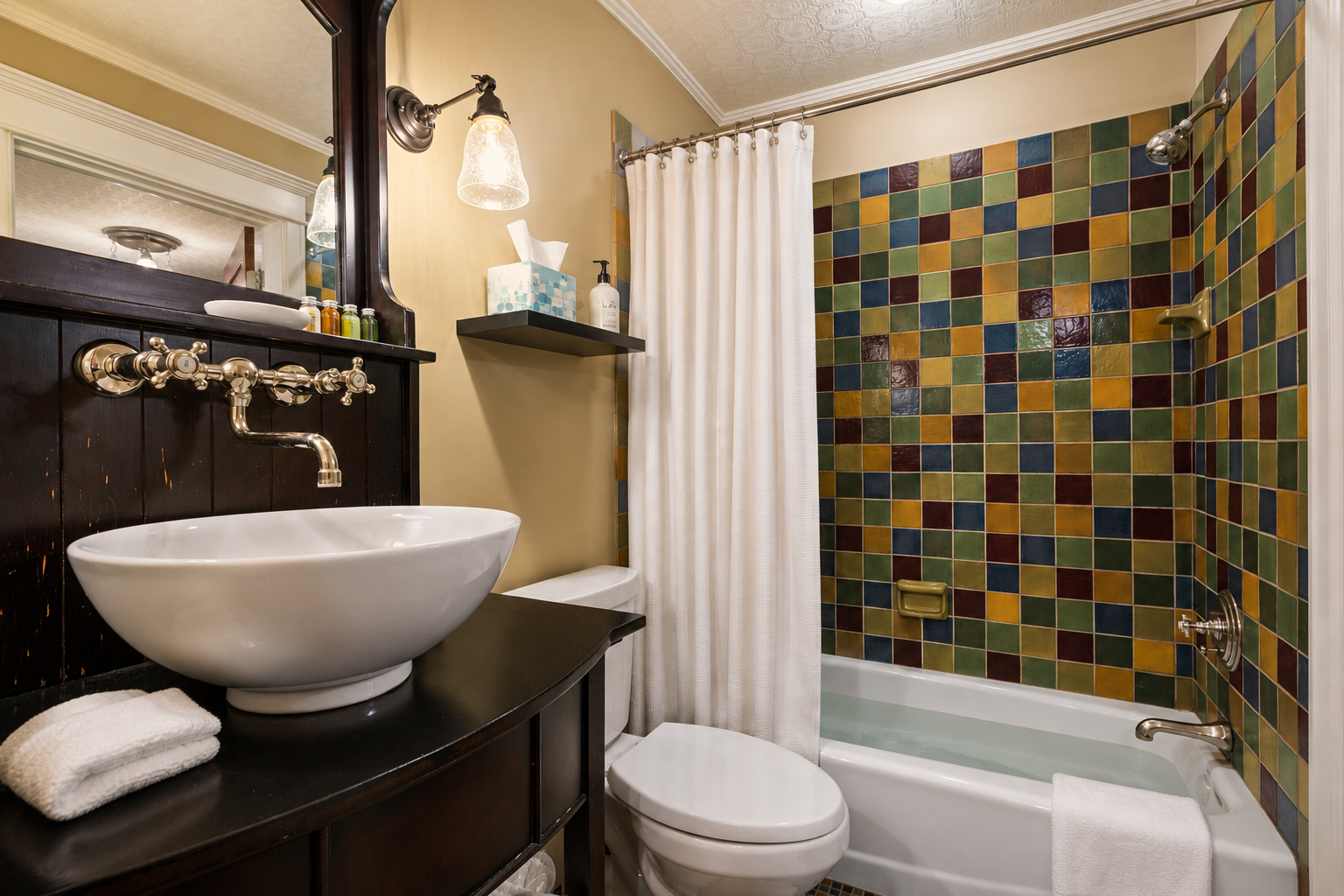 Your private bathroom features a colorful mosaic tile shower, a sleek vessel sink with vintage-inspired fixtures, and soft towels—everything you need for a refreshing start or relaxing end to your day.