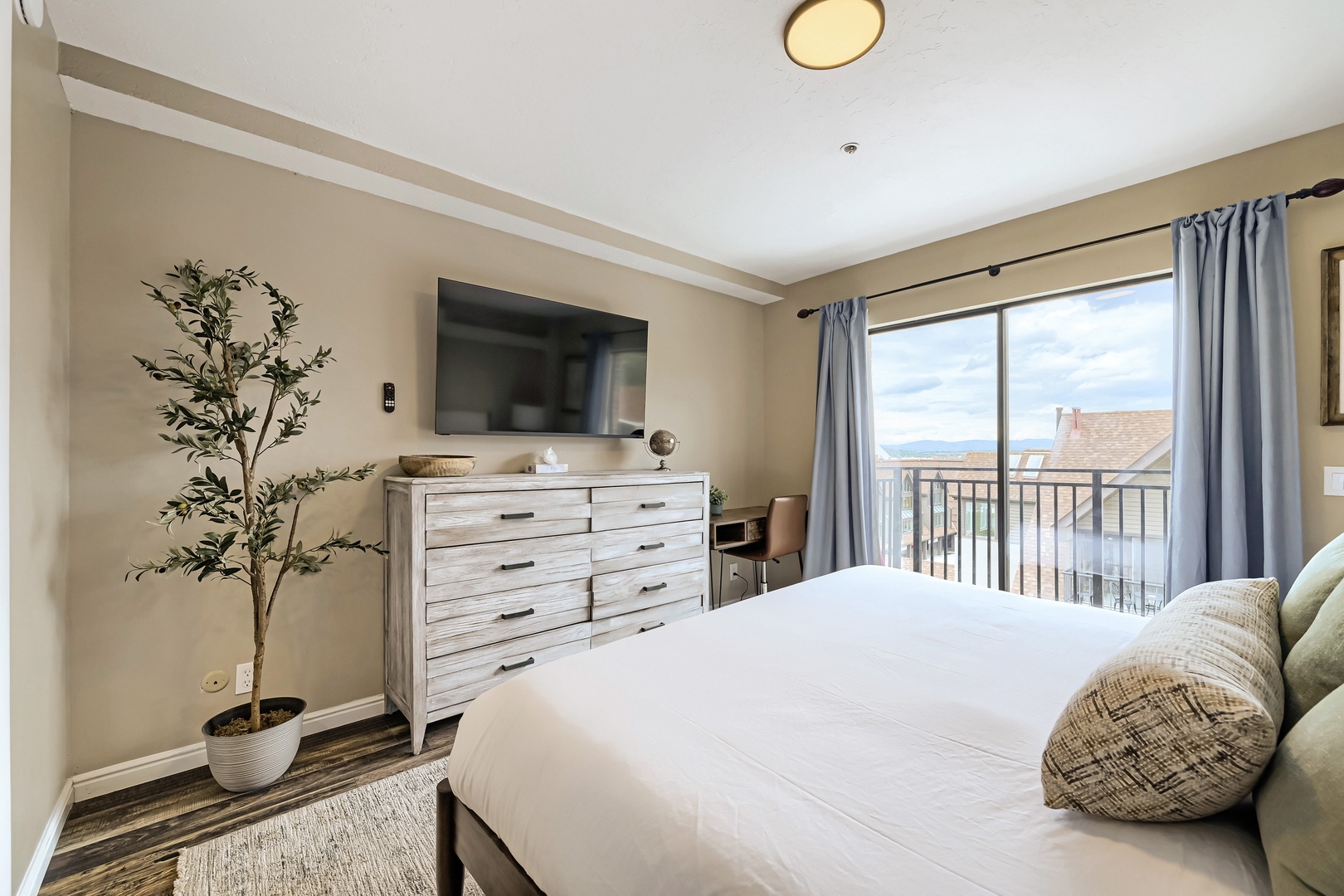 Step into your serene bedroom retreat where a plush bed awaits and a private balcony frames views of nearby rooftops and distant horizons, perfect for morning coffee or evening relaxation.
