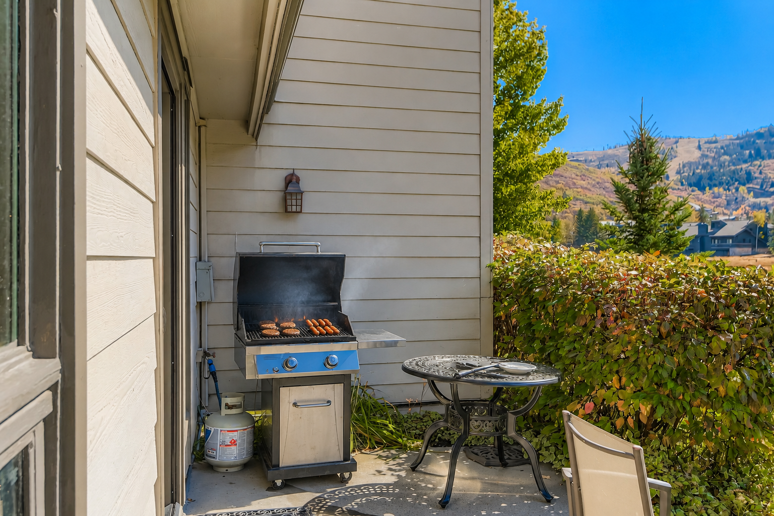 This private patio offers mountain views and a gas grill perfect for outdoor dining, with a cozy table set for meals in the fresh air.